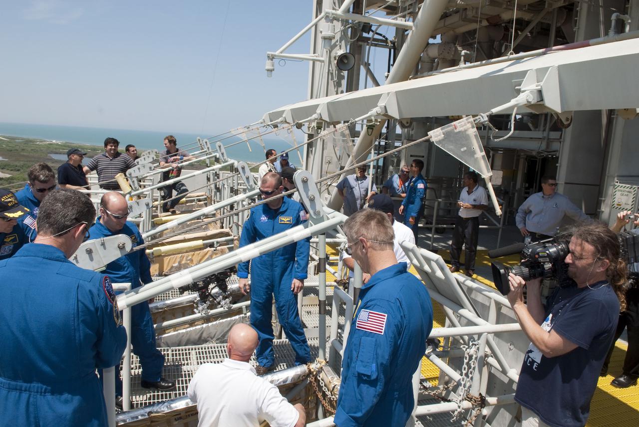 CAPE CANAVERAL, Fla. - On Launch Pad 39A at NASA's Kennedy Space Center, NASA cameraman Troy Cryder, right, documents the emergency exit training of space shuttle Atlantis' STS-132 crew.  In the blue flight suits, from left, facing the camera, are Commander Ken Ham; Mission Specialists Steve Bowen and Garrett Reisman; and Pilot Tony Antonelli.  Facing away from the camera are Mission Specialists Michael Good, left, and Piers Sellers.  The pad's escape system includes seven baskets suspended from seven slidewires that extend from the fixed service structure to a landing zone 1,200 feet west of the pad.  The crew is participating in training in preparation for their Terminal Countdown Demonstration Test, or TCDT, a dress rehearsal for launch.  TCDT provides each shuttle crew and launch team the opportunity to participate in various simulated countdown activities, including equipment familiarization and emergency procedures.  On the STS-132 mission, the six-member crew will deliver an Integrated Cargo Carrier, or ICC, and the Russian-built Mini-Research Module-1, or MRM-1, to the International Space Station aboard space shuttle Atlantis.  The ICC is an unpressurized flat bed pallet and keel yoke assembly used to support the transfer of exterior cargo from the shuttle to the space station.  The MRM-1, known as Rassvet, is the second in a series of new pressurized components for Russia and will be permanently attached to the Earth-facing port of the Zarya control module. Rassvet, which translates to 'dawn,' will be used for cargo storage and will provide an additional docking port to the station.  STS-132 is the 34th mission to the station and the 132nd shuttle mission overall.   Atlantis is targeted to launch on May 14 at 2:19 p.m.  For information on the STS-132 mission, visit http:__www.nasa.gov_mission_pages_shuttle_shuttlemissions_sts132_index.html. Photo credit: NASA_Jim Grossmann