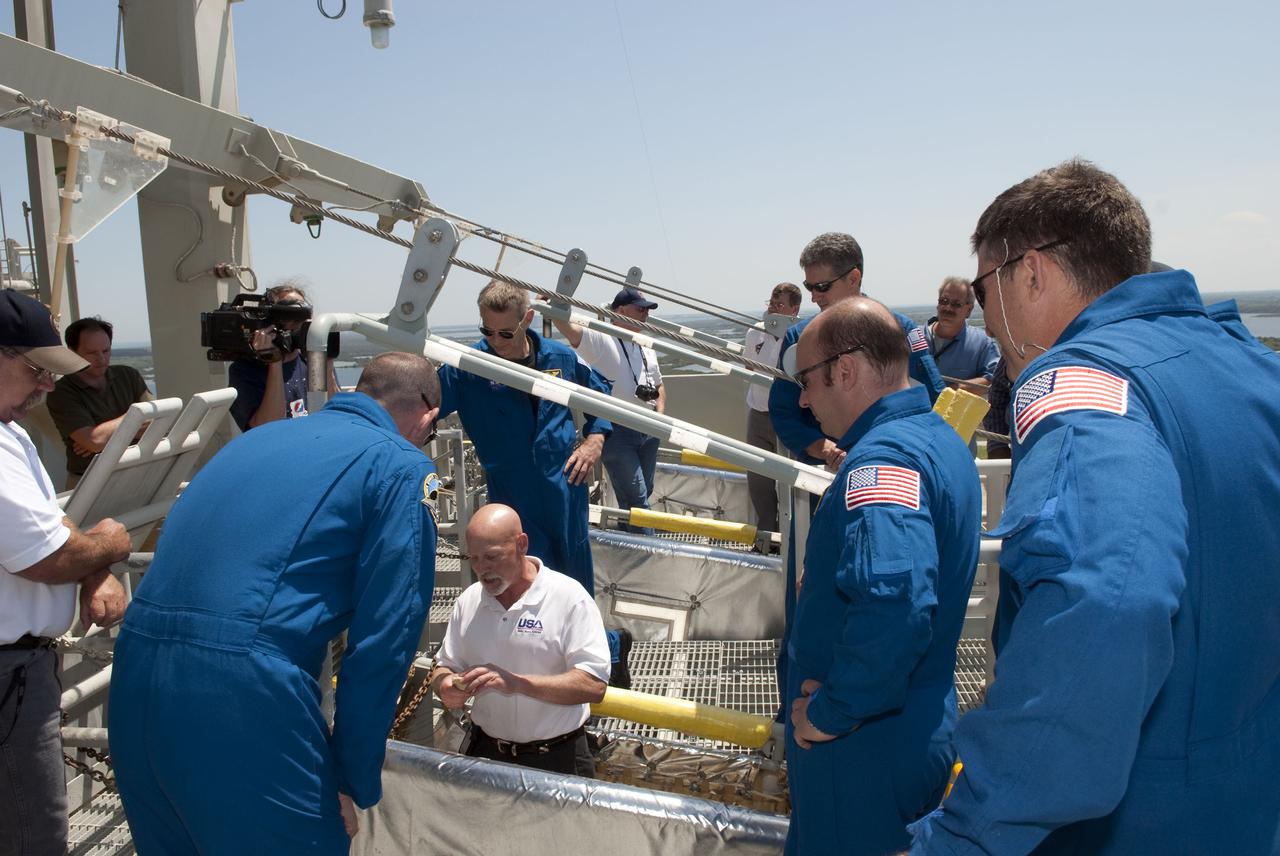 CAPE CANAVERAL, Fla. - On Launch Pad 39A at NASA's Kennedy Space Center, the members of space shuttle Atlantis' STS-132 crew receive instruction on the operation of the pad's slidewire basket system during emergency exit training.  In the blue flight suits, from left, facing the camera, are Mission Specialists Piers Sellers, left, and Michael Good.  Facing away from the camera are, from left, Pilot Tony Antonelli and Mission Specialists Garrett Reisman and Steve Bowen.  The pad's escape system includes seven baskets suspended from seven slidewires that extend from the fixed service structure to a landing zone 1,200 feet west of the pad.  The crew is participating in training in preparation for their Terminal Countdown Demonstration Test, or TCDT, a dress rehearsal for launch.  TCDT provides each shuttle crew and launch team the opportunity to participate in various simulated countdown activities, including equipment familiarization and emergency procedures.  On the STS-132 mission, the six-member crew will deliver an Integrated Cargo Carrier, or ICC, and the Russian-built Mini-Research Module-1, or MRM-1, to the International Space Station aboard space shuttle Atlantis.  The ICC is an unpressurized flat bed pallet and keel yoke assembly used to support the transfer of exterior cargo from the shuttle to the space station.  The MRM-1, known as Rassvet, is the second in a series of new pressurized components for Russia and will be permanently attached to the Earth-facing port of the Zarya control module. Rassvet, which translates to 'dawn,' will be used for cargo storage and will provide an additional docking port to the station.  STS-132 is the 34th mission to the station and the 132nd shuttle mission overall.   Atlantis is targeted to launch on May 14 at 2:19 p.m.  For information on the STS-132 mission, visit http:__www.nasa.gov_mission_pages_shuttle_shuttlemissions_sts132_index.html. Photo credit: NASA_Jim Grossmann