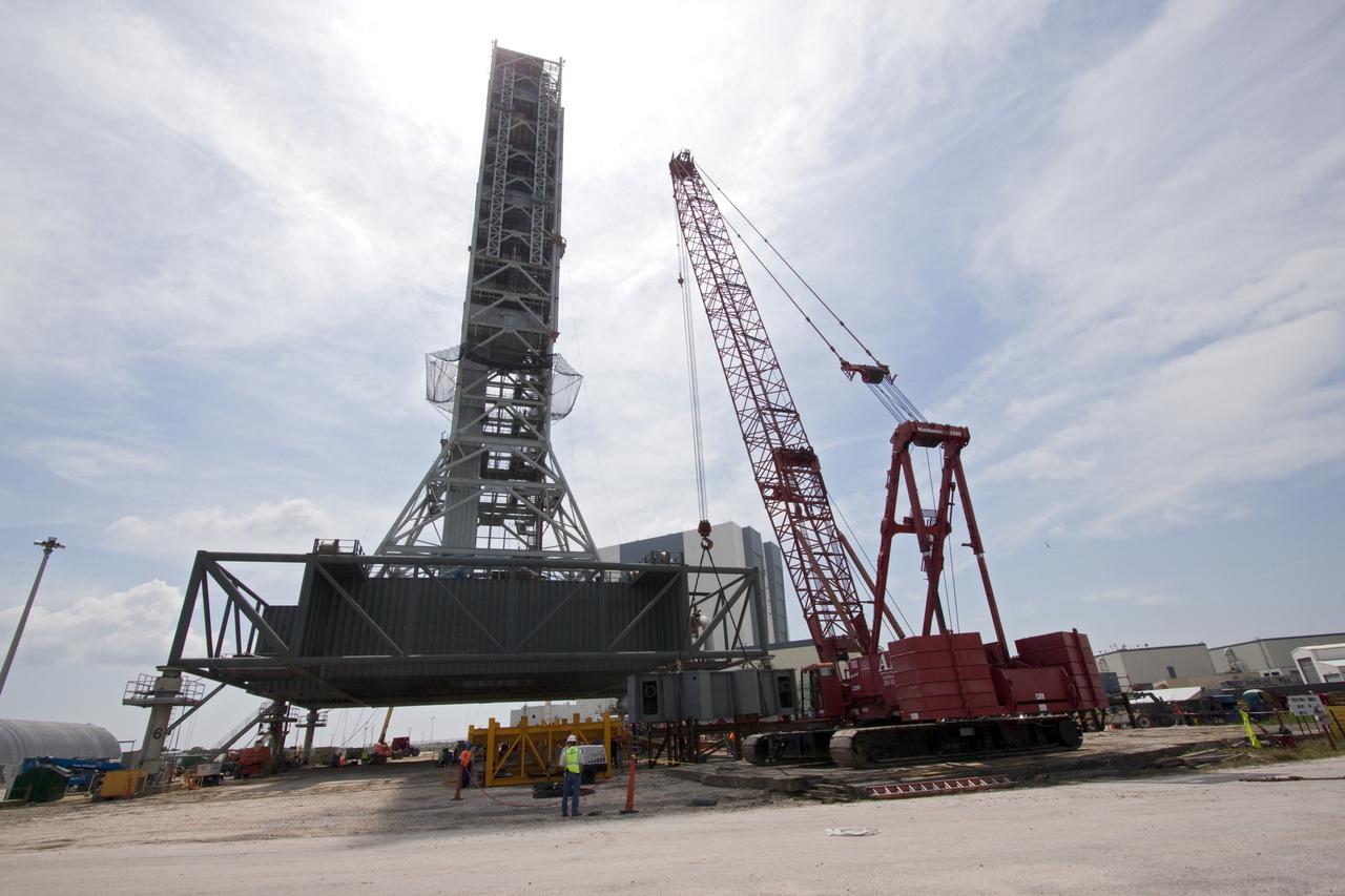 CAPE CANAVERAL, Fla. – At NASA's Kennedy Space Center in Florida, workers supervise the lift of the third segment of the launch mount for a new mobile launcher, or ML, being constructed to support NASA's future human spaceflight program from the tractor-trailer on which it arrived.  The construction is taking place in the mobile launcher park site north of Kennedy's Vehicle Assembly Building.  The new launcher is 355 feet tall and has multiple platforms for personnel access. The base of the launcher is lighter than space shuttle mobile launcher platforms so the crawler-transporter can pick up the heavier load of the tower and a taller rocket. For information on NASA's future plans, visit http:__www.nasa.gov. Photo credit: NASA_Jack Pfaller
