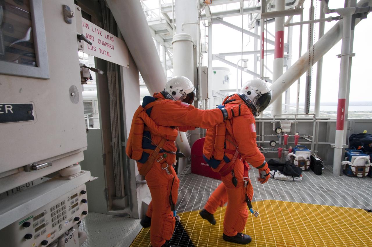 CAPE CANAVERAL, Fla. - On Launch Pad 39A at NASA's Kennedy Space Center, STS-132 Mission Specialists Piers Sellers, left, and Steve Bowen, dressed in their orange launch-and-entry suits, practice emergency exit procedures.  Evacuation from the pad's 195-foot level in the event of an emergency is made possible by seven baskets suspended from seven slidewires that extend from the fixed service structure to a landing zone 1,200 feet west of the pad.  The crew is participating in a launch dress rehearsal, called the Terminal Countdown Demonstration Test, or TCDT.  TCDT provides each shuttle crew and launch team the opportunity to participate in various simulated countdown activities, including equipment familiarization and emergency procedures.  On the STS-132 mission, the six-member crew will deliver an Integrated Cargo Carrier, or ICC, and the Russian-built Mini-Research Module-1, or MRM-1, to the International Space Station aboard space shuttle Atlantis.  The ICC is an unpressurized flat bed pallet and keel yoke assembly used to support the transfer of exterior cargo from the shuttle to the space station.  The MRM-1, known as Rassvet, is the second in a series of new pressurized components for Russia and will be permanently attached to the Earth-facing port of the Zarya control module. Rassvet, which translates to 'dawn,' will be used for cargo storage and will provide an additional docking port to the station.  STS-132 is the 34th mission to the station and the 132nd shuttle mission overall.   Atlantis is targeted to launch on May 14 at 2:19 p.m.  For information on the STS-132 mission, visit http:__www.nasa.gov_mission_pages_shuttle_shuttlemissions_sts132_index.html. Photo credit: NASA_Jack Pfaller
