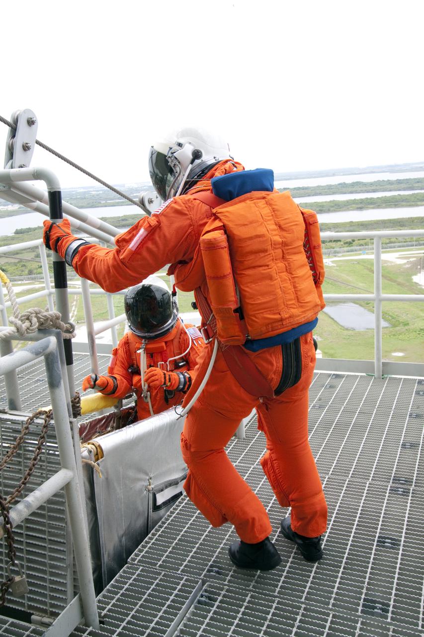 CAPE CANAVERAL, Fla. - On Launch Pad 39A at NASA's Kennedy Space Center, STS-132 Commander Ken Ham and Pilot Tony Antonelli (in basket), dressed in their orange launch-and-entry suits, position themselves jump into a slidewire basket as they practice emergency exit procedures at the pad.  Evacuation from the pad's 195-foot level in the event of an emergency is made possible by seven baskets suspended from seven slidewires that extend from the fixed service structure to a landing zone 1,200 feet west of the pad.  The crew is participating in a launch dress rehearsal, called the Terminal Countdown Demonstration Test, or TCDT.  TCDT provides each shuttle crew and launch team the opportunity to participate in various simulated countdown activities, including equipment familiarization and emergency procedures.  On the STS-132 mission, the six-member crew will deliver an Integrated Cargo Carrier, or ICC, and the Russian-built Mini-Research Module-1, or MRM-1, to the International Space Station aboard space shuttle Atlantis.  The ICC is an unpressurized flat bed pallet and keel yoke assembly used to support the transfer of exterior cargo from the shuttle to the space station.  The MRM-1, known as Rassvet, is the second in a series of new pressurized components for Russia and will be permanently attached to the Earth-facing port of the Zarya control module. Rassvet, which translates to 'dawn,' will be used for cargo storage and will provide an additional docking port to the station.  STS-132 is the 34th mission to the station and the 132nd shuttle mission overall.   Atlantis is targeted to launch on May 14 at 2:19 p.m.  For information on the STS-132 mission, visit http:__www.nasa.gov_mission_pages_shuttle_shuttlemissions_sts132_index.html. Photo credit: NASA_Jack Pfaller