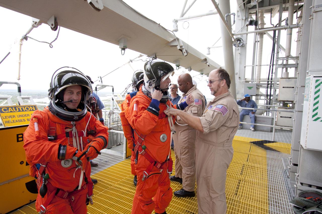 CAPE CANAVERAL, Fla. - At Launch Pad 39A at NASA's Kennedy Space Center in Florida, STS-132 Mission Specialist Garrett Reisman, left, and Commander Ken Ham, dressed in their orange launch-and-entry suits, remove their helmets following practice of emergency exit procedures.  Evacuation from the pad's 195-foot level in the event of an emergency is made possible by seven baskets suspended from seven slidewires that extend from the fixed service structure to a landing zone 1,200 feet west of the pad.  The crew is participating in a launch dress rehearsal, called the Terminal Countdown Demonstration Test, or TCDT.  TCDT provides each shuttle crew and launch team the opportunity to participate in various simulated countdown activities, including equipment familiarization and emergency procedures.  On the STS-132 mission, the six-member crew will deliver an Integrated Cargo Carrier, or ICC, and the Russian-built Mini-Research Module-1, or MRM-1, to the International Space Station aboard space shuttle Atlantis.  The ICC is an unpressurized flat bed pallet and keel yoke assembly used to support the transfer of exterior cargo from the shuttle to the space station.  The MRM-1, known as Rassvet, is the second in a series of new pressurized components for Russia and will be permanently attached to the Earth-facing port of the Zarya control module. Rassvet, which translates to 'dawn,' will be used for cargo storage and will provide an additional docking port to the station.  STS-132 is the 34th mission to the station and the 132nd shuttle mission overall.   Atlantis is targeted to launch on May 14 at 2:19 p.m.  For information on the STS-132 mission, visit http:__www.nasa.gov_mission_pages_shuttle_shuttlemissions_sts132_index.html. Photo credit: NASA_Jack Pfaller
