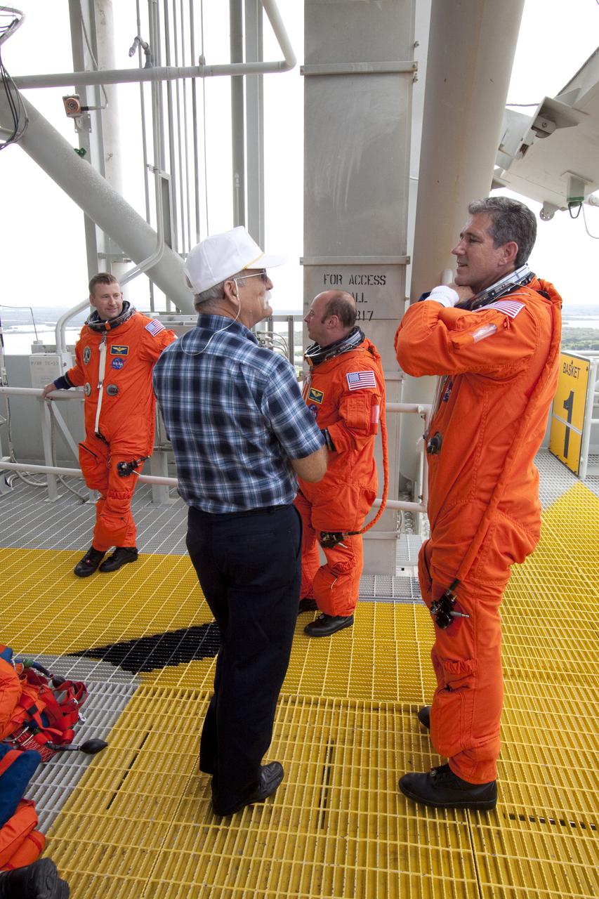 CAPE CANAVERAL, Fla. - At Launch Pad 39A at NASA's Kennedy Space Center in Florida, from left, STS-132 Commander Ken Ham and Mission Specialists Garrett Reisman and Michael Good, dressed in their orange launch-and-entry suits, take a moment to relax following practice of emergency exit procedures.  Evacuation from the pad's 195-foot level in the event of an emergency is made possible by seven baskets suspended from seven slidewires that extend from the fixed service structure to a landing zone 1,200 feet west of the pad.  The crew is participating in a launch dress rehearsal, called the Terminal Countdown Demonstration Test, or TCDT.  TCDT provides each shuttle crew and launch team the opportunity to participate in various simulated countdown activities, including equipment familiarization and emergency procedures.  On the STS-132 mission, the six-member crew will deliver an Integrated Cargo Carrier, or ICC, and the Russian-built Mini-Research Module-1, or MRM-1, to the International Space Station aboard space shuttle Atlantis.  The ICC is an unpressurized flat bed pallet and keel yoke assembly used to support the transfer of exterior cargo from the shuttle to the space station.  The MRM-1, known as Rassvet, is the second in a series of new pressurized components for Russia and will be permanently attached to the Earth-facing port of the Zarya control module. Rassvet, which translates to 'dawn,' will be used for cargo storage and will provide an additional docking port to the station.  STS-132 is the 34th mission to the station and the 132nd shuttle mission overall.   Atlantis is targeted to launch on May 14 at 2:19 p.m.  For information on the STS-132 mission, visit http:__www.nasa.gov_mission_pages_shuttle_shuttlemissions_sts132_index.html. Photo credit: NASA_Jack Pfaller