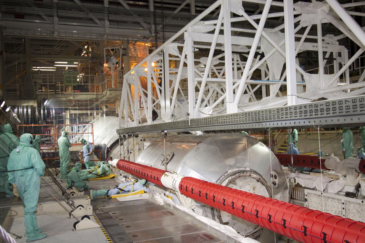 CAPE CANAVERAL, Fla. - In Orbiter Processing Facility-3 at NASA's Kennedy Space Center in Florida, United Space Alliance workers perform their individual tasks in attaching a lifting device to the multi-purpose logistics module Leonardo and an ammonia tank assembly in space shuttle Discovery's payload bay.  Discovery landed on Runway 33 at Kennedy's Shuttle Landing Facility at 9:08 a.m. EDT April 20 after 15 days in space, completing the more than 6.2-million-mile STS-131 mission on orbit 238.  The seven-member STS-131 crew carried the multi-purpose logistics module Leonardo, filled with supplies, a new crew sleeping quarters and science racks that were transferred to the International Space Station's laboratories.  Leonardo now will be modified into a permanent multi-purpose module, or PMM, and left aboard the station on space shuttle Discovery's STS-133 mission, targeted for launch Sept. 16.  For information on the STS-131 mission, visit http:__www.nasa.gov_mission_pages_shuttle_shuttlemissions_sts131_index.html.  For information on the STS-133 mission, visit http:__www.nasa.gov_mission_pages_shuttle_shuttlemissions_sts133_index.html.  Photo credit: NASA_Jack Pfaller