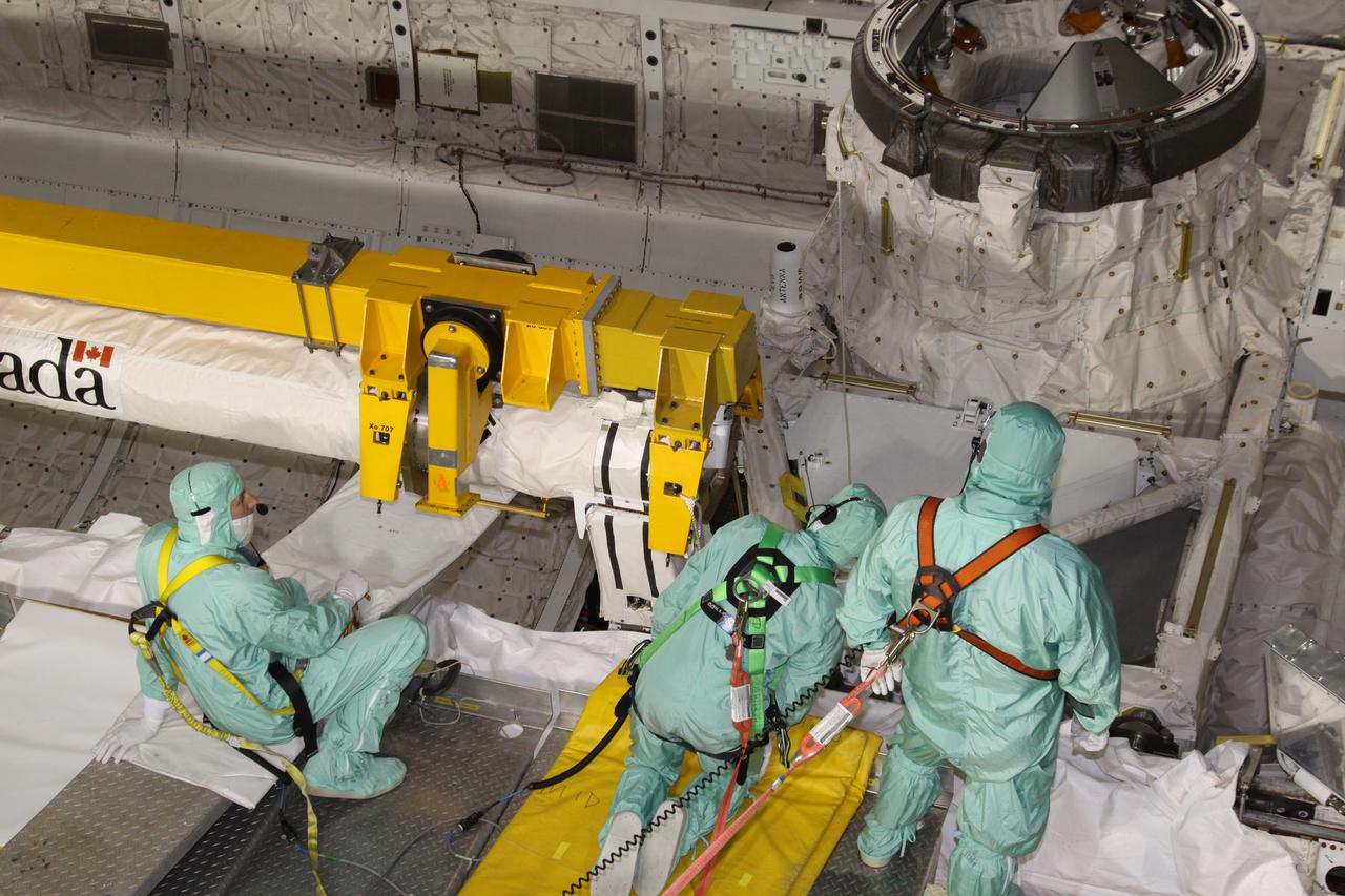 CAPE CANAVERAL, Fla. - In Orbiter Processing Facility-3 at NASA's Kennedy Space Center in Florida, workers ensure that the orbiter boom sensor system, or OBSS, is ready to be lifted from space shuttle Discovery's payload bay.  The workers are dressed in clean-room attire, known as 'bunny suits.' The 50-foot-long OBSS attaches to the end of the shuttle’s robotic arm and supports the cameras and laser systems used to inspect the shuttle’s thermal protection system while in space.  The OBSS' inspection boom assembly, or IBA, is removed from the arm every other processing flow for a detailed inspection. After five consecutive flights, all IBA internal components are submitted to a thorough electrical checkout in Kennedy's Remote Manipulator System Lab.  Discovery next will deliver the first Permanent Multi-purpose Module, or PMM; the Express Logistics Carrier 4; and critical spare parts to the International Space Station on the STS-133 mission.  Launch is targeted for Sept. 16.  Photo credit: NASA_Jack Pfaller
