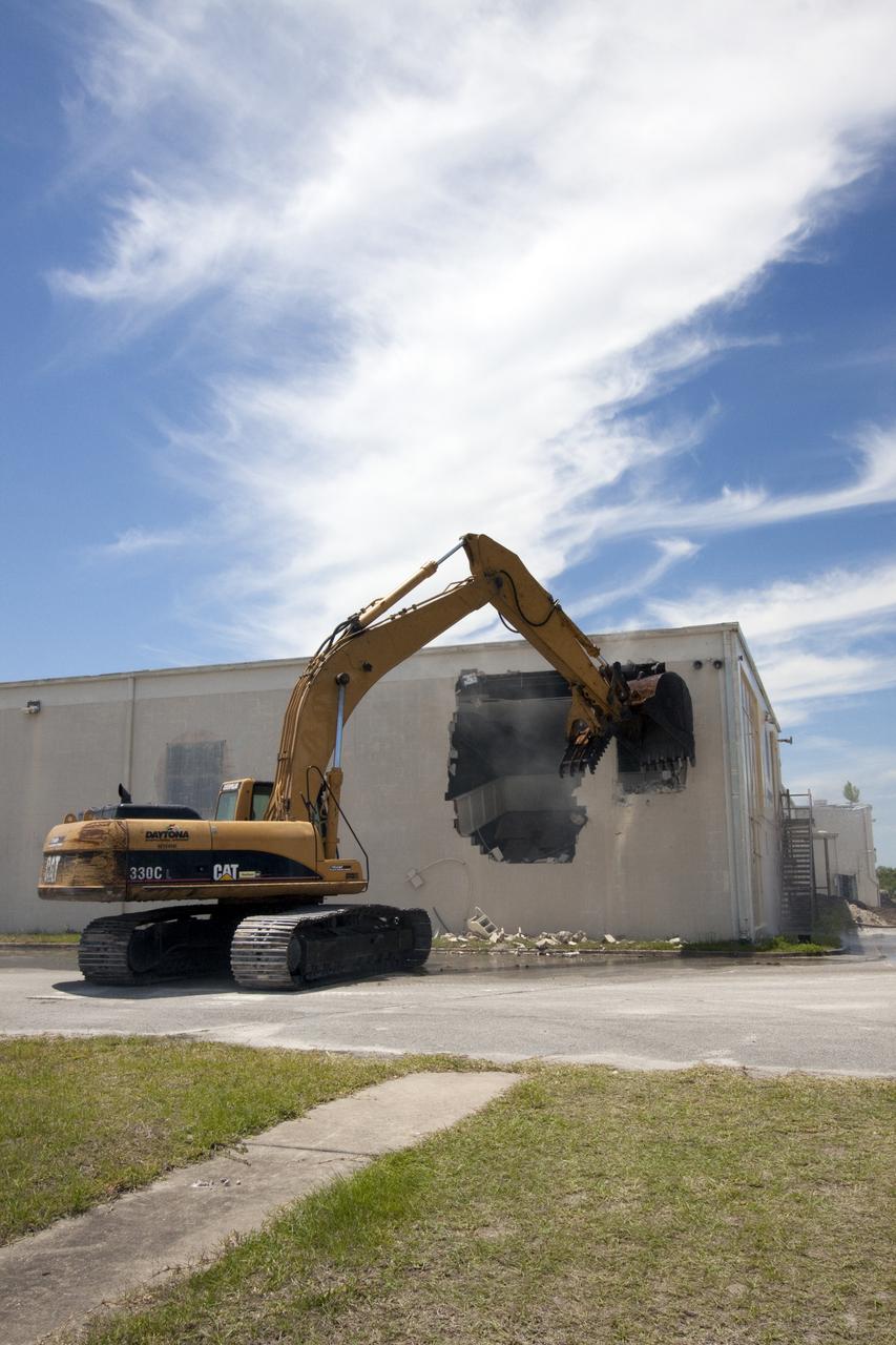CAPE CANAVERAL, Fla. – At Cape Canaveral Air Force Station in Florida, a Caterpillar 330 track-hoe rips through the wall of the Mercury Mission Control Center.  The original building, constructed between 1956 and 1958, was last modified in 1963.  The center succumbed to the two worst enemies of structures along the space coast - time and salt air - necessitating that it be demolished as a safety measure.  The facility served as mission control during all the Project Mercury missions, as well as the first three flights of the Gemini Program. The center housed the flight controllers whose duty was to take over flight control after liftoff and follow it through until splashdown. Additionally, it supported vehicle checkout, spacecraft tracking, and astronaut training. With Gemini IV, mission control moved to Houston, and the facility took on the roles of launch control and tracking station. In 1999, much of the equipment and furnishings from the flight control area was moved to Kennedy Space Center's Visitor Complex.  A re-created mission control room currently is on display in the complex's Dr. Kurt H. Debus Conference Facility.  Speegle II of Cocoa, Fla., was awarded the contract for the deconstruction project.  Frank-Lin Excavating is performing the demolition for Sunrise Systems of Brevard, a subcontractor to Speegle II.  Photo credit: NASA_Jack Pfaller