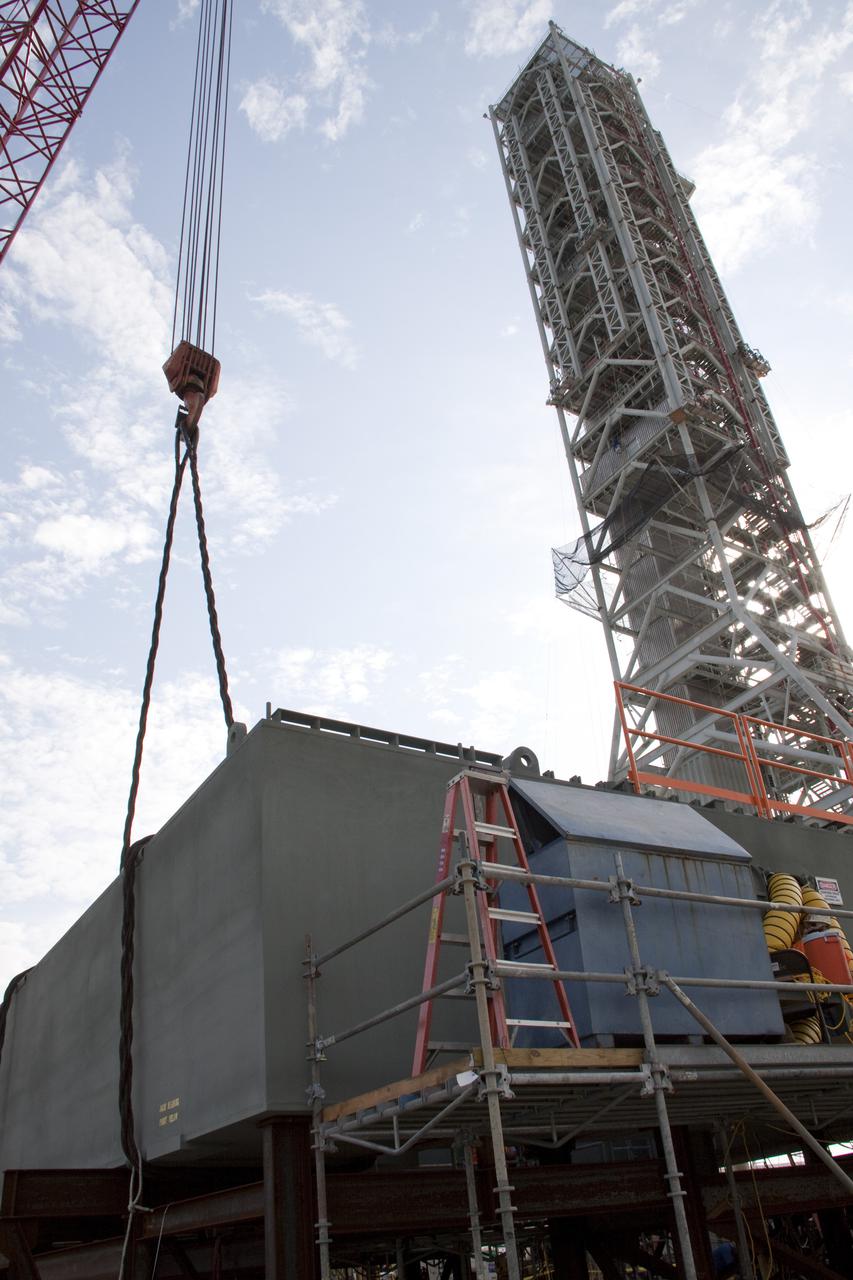 CAPE CANAVERAL, Fla. – At NASA's Kennedy Space Center in Florida, a crane is enlisted to lift a section of the launch mount for a new mobile launcher, or ML, being constructed to support NASA's future human spaceflight program.  All eight segments of the mount have been delivered to Kennedy.  The launcher's tower looms overhead, at right.  The construction is taking place in Launch Complex 39 in the mobile launcher park site north of Kennedy's Vehicle Assembly Building.  The new launcher is 355 feet tall and has multiple platforms for personnel access. The base of the launcher is lighter than space shuttle mobile launcher platforms so the crawler-transporter can pick up the heavier load of the tower and a taller rocket. For information on NASA's future plans, visit http:__www.nasa.gov. Photo credit: NASA_Amanda Diller