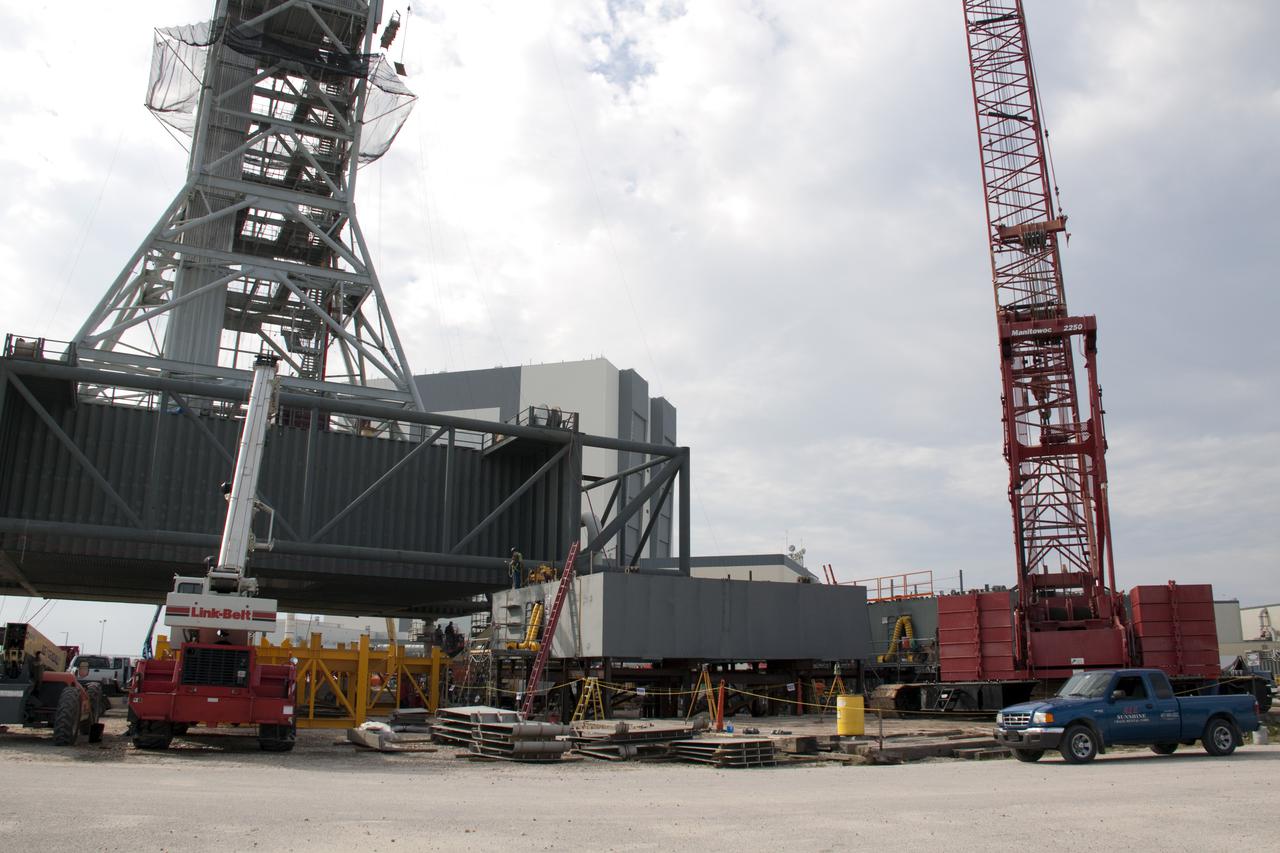 CAPE CANAVERAL, Fla. – At NASA's Kennedy Space Center in Florida, work progresses on the construction of the launch mount for a new mobile launcher, or ML, which will support NASA's future human spaceflight program, following the arrival of all eight segments.  The base of the launcher's tower is at left.  The construction is taking place in Launch Complex 39 in the mobile launcher park site north of Kennedy's Vehicle Assembly Building.  The new launcher is 355 feet tall and has multiple platforms for personnel access. The base of the launcher is lighter than space shuttle mobile launcher platforms so the crawler-transporter can pick up the heavier load of the tower and a taller rocket. For information on NASA's future plans, visit http:__www.nasa.gov. Photo credit: NASA_Amanda Diller