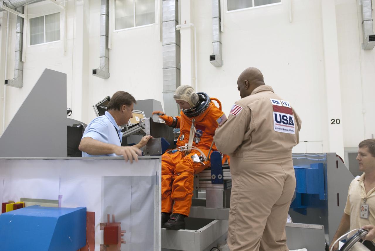 CAPE CANAVERAL, Fla. – In the Operations and Checkout Building at NASA's Kennedy Space Center in Florida, United Space Alliance EV_IV Integrated Operations work control specialist Jennifer Peterson, dressed in a flight-and-entry suit, stands in for an astronaut for a demonstration inside a mock-up of an Orion crew exploration vehicle. The mock-up details the interior components of the vehicle including seat layout and the subsystem components on the outside of the pressure vessel. Orion mock-ups also have been used to verify accessibility of the servicing locations at the launch pad and in the Vehicle Assembly Building. For information on the development of the Orion capsule, visit www.nasa.gov_orion. Photo credit: NASA_Jim Grossmann