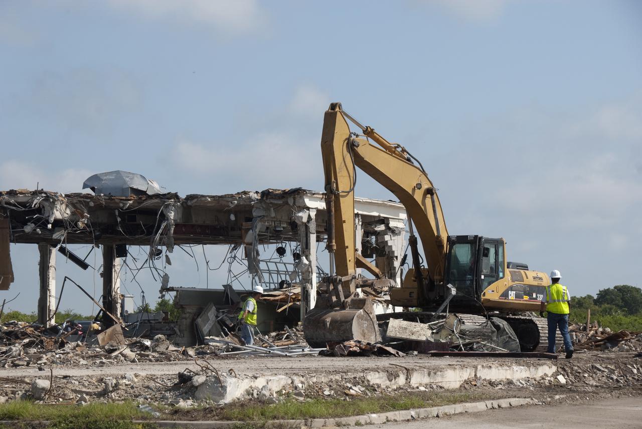 CAPE CANAVERAL, Fla. – At Cape Canaveral Air Force Station in Florida, workers take time out from operation of a Caterpillar 330 track-hoe and the demolition of NASA's Mercury Mission Control Center to determine their next steps.  The deconstruction project began on April 28. The original building, constructed between 1956 and 1958, was last modified in 1963.  The center succumbed to the two worst enemies of structures along the space coast - time and salt air - necessitating that it be demolished as a safety measure.  The facility served as mission control during all the Project Mercury missions, as well as the first three flights of the Gemini Program. The center housed the flight controllers whose duty was to take over flight control after liftoff and follow it through until splashdown. Additionally, it supported vehicle checkout, spacecraft tracking, and astronaut training. With Gemini IV, mission control moved to Houston, and the facility took on the roles of launch control and tracking station. In 1999, much of the equipment and furnishings from the flight control area was moved to Kennedy Space Center's Visitor Complex.  A re-created mission control room currently is on display in the complex's Dr. Kurt H. Debus Conference Facility.  Speegle II of Cocoa, Fla., was awarded the contract for the deconstruction project.  Frank-Lin Excavating is performing the demolition for Sunrise Systems of Brevard, a subcontractor to Speegle II.  Photo credit: NASA_Jack Pfaller