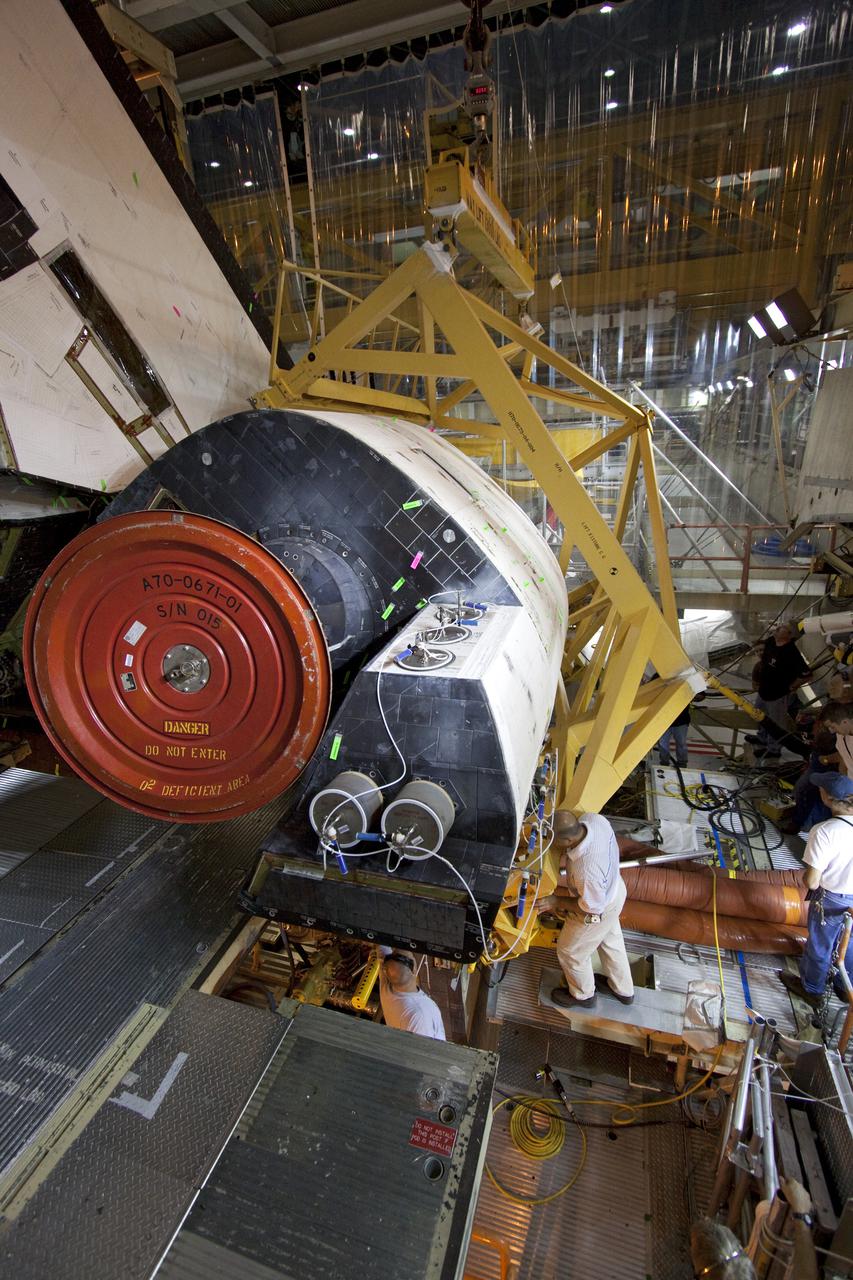 CAPE CANAVERAL, Fla. – Inside Orbiter Processing Facility-3 at Kennedy Space Center in Florida, United Space Alliance technicians prepare to remove the right-hand orbital maneuvering system, or OMS, pod from Discovery. Removal of the OMS pods is part of the orbiter processing activities to prepare Discovery for its next launch, the STS-133 mission. The STS-133 mission to the International Space Station is targeted for launch in the fall of 2010. Discovery’s six-person crew will take important spare parts to the International Space Station along with the Express Logistics Carrier 4. Photo credit: NASA_Jack Pfaller