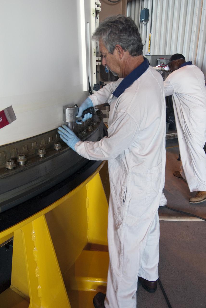 CAPE CANAVERAL, Fla. -- A technician in the Rotation, Processing and Surge Facility at NASA's Kennedy Space Center in Florida, loosens a bolt to remove the segment's aft handling ring before it is moved onto a transportation and storage pallet.   The segments will be used for space shuttle  Atlantis on what currently is planned as the 'launch on need,' or potential rescue mission for the final shuttle flight, Endeavour's STS-134 mission. For information, visit www.nasa.gov_shuttle. Photo credit: NASA_Cory Huston