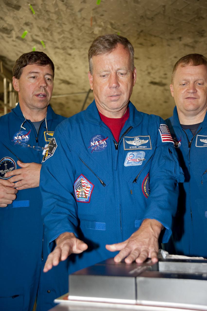 CAPE CANAVERAL, Fla. -- In Orbiter Processing Facility-3 at NASA's Kennedy Space Center in Florida, STS-133 Pilot Eric Boe (right)  and Mission Specialist Michael Barratt look on as Commander Steve Lindsey (center) inspects a piece of hardware that will fly on their mission.    The astronauts are at Kennedy for the Crew Equipment Interface Test, or CEIT, which provides the crew with hands-on training and observation of shuttle and flight hardware for their mission to the International Space Station. Launch of the STS-133 mission on space shuttle Discovery is targeted for Nov. 1 at 4:33 p.m. EDT. Photo credit: NASA_Kim Shiflett