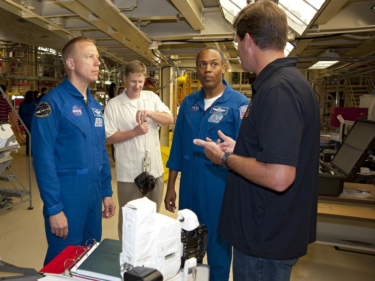 CAPE CANAVERAL, Fla. -- In Orbiter Processing Facility-3 at NASA's Kennedy Space Center in Florida, STS-133 Mission Specialists Tim Kopra (left) and Alvin Drew listen intently as a technician describes a piece of equipment they'll use while in space.    The astronauts are at Kennedy for the Crew Equipment Interface Test, or CEIT, which provides the crew with hands-on training and observation of shuttle and flight hardware for their mission to the International Space Station. Launch of the STS-133 mission on space shuttle Discovery is targeted for Nov. 1 at 4:33 p.m. EDT. Photo credit: NASA_Kim Shiflett