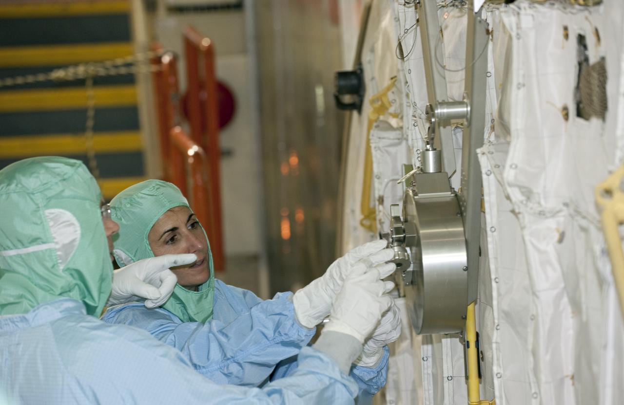CAPE CANAVERAL, Fla. -- In Orbiter Processing Facility-3 at NASA's Kennedy Space Center in Florida, STS-133 Pilot Eric Boe (out of frame) and Mission Specialist Nicole Stott listen to a technician as he describes an element of the shuttle's payload bay.    The astronauts are at Kennedy for the Crew Equipment Interface Test, or CEIT, which provides the crew with hands-on training and observation of shuttle and flight hardware for their mission to the International Space Station. Launch of the STS-133 mission on space shuttle Discovery is targeted for Nov. 1 at 4:33 p.m. EDT. Photo credit: NASA_Kim Shiflett