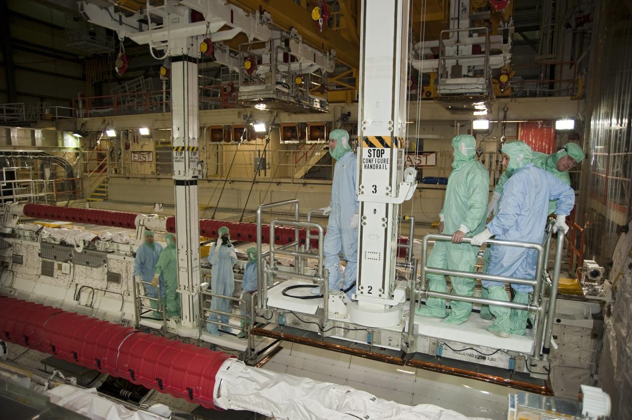 CAPE CANAVERAL, Fla. -- Attired in clean-room gear, known as 'bunny suits,' the STS-133 crew members look into the shuttle's payload bay in Orbiter Processing Facility-3 at NASA's Kennedy Space Center in Florida.    The astronauts are at Kennedy for the Crew Equipment Interface Test, or CEIT, which provides the crew with hands-on training and observation of shuttle and flight hardware for their mission to the International Space Station. Launch of the STS-133 mission on space shuttle Discovery is targeted for Nov. 1 at 4:33 p.m. EDT. Photo credit: NASA_Kim Shiflett