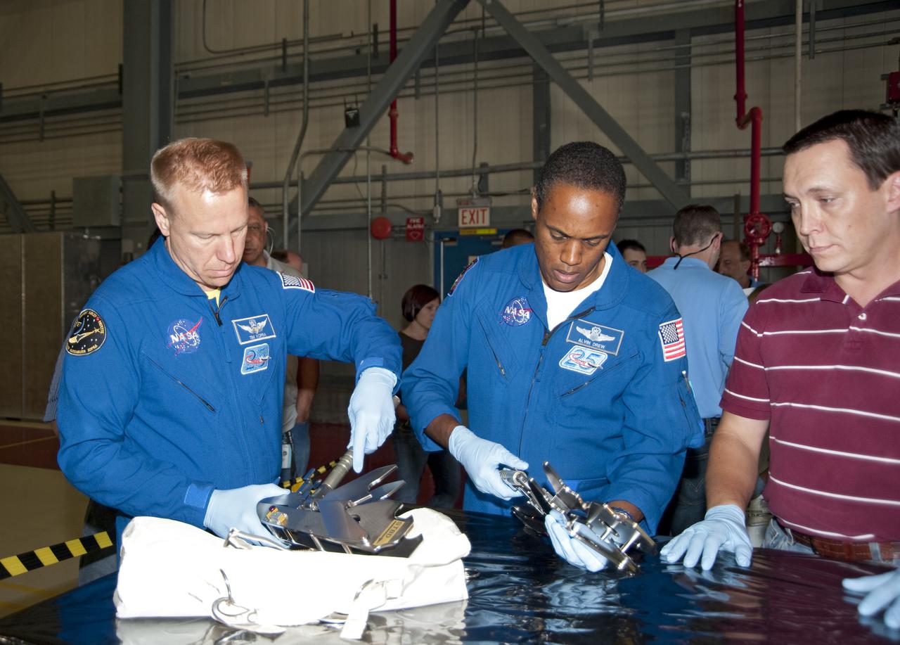 CAPE CANAVERAL, Fla. -- In Orbiter Processing Facility-3 at NASA's Kennedy Space Center in Florida, STS-133 Mission Specialists Tim Kopra (left) and Alvin drew examine hardware they will use while in space.    The astronauts are at Kennedy for the Crew Equipment Interface Test, or CEIT, which provides the crew with hands-on training and observation of shuttle and flight hardware for their mission to the International Space Station. Launch of the STS-133 mission on space shuttle Discovery is targeted for Nov. 1 at 4:33 p.m. EDT. Photo credit: NASA_Kim Shiflett