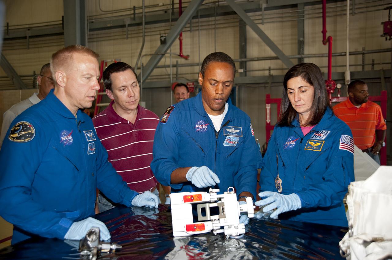 CAPE CANAVERAL, Fla. -- In Orbiter Processing Facility-3 at NASA's Kennedy Space Center in Florida, STS-133 Mission Specialists Tim Kopra (left), Alvin Drew and Nicole Stott review the hardware that will fly on their mission.    The astronauts are at Kennedy for the Crew Equipment Interface Test, or CEIT, which provides the crew with hands-on training and observation of shuttle and flight hardware for their mission to the International Space Station. Launch of the STS-133 mission on space shuttle Discovery is targeted for Nov. 1 at 4:33 p.m. EDT. Photo credit: NASA_Kim Shiflett