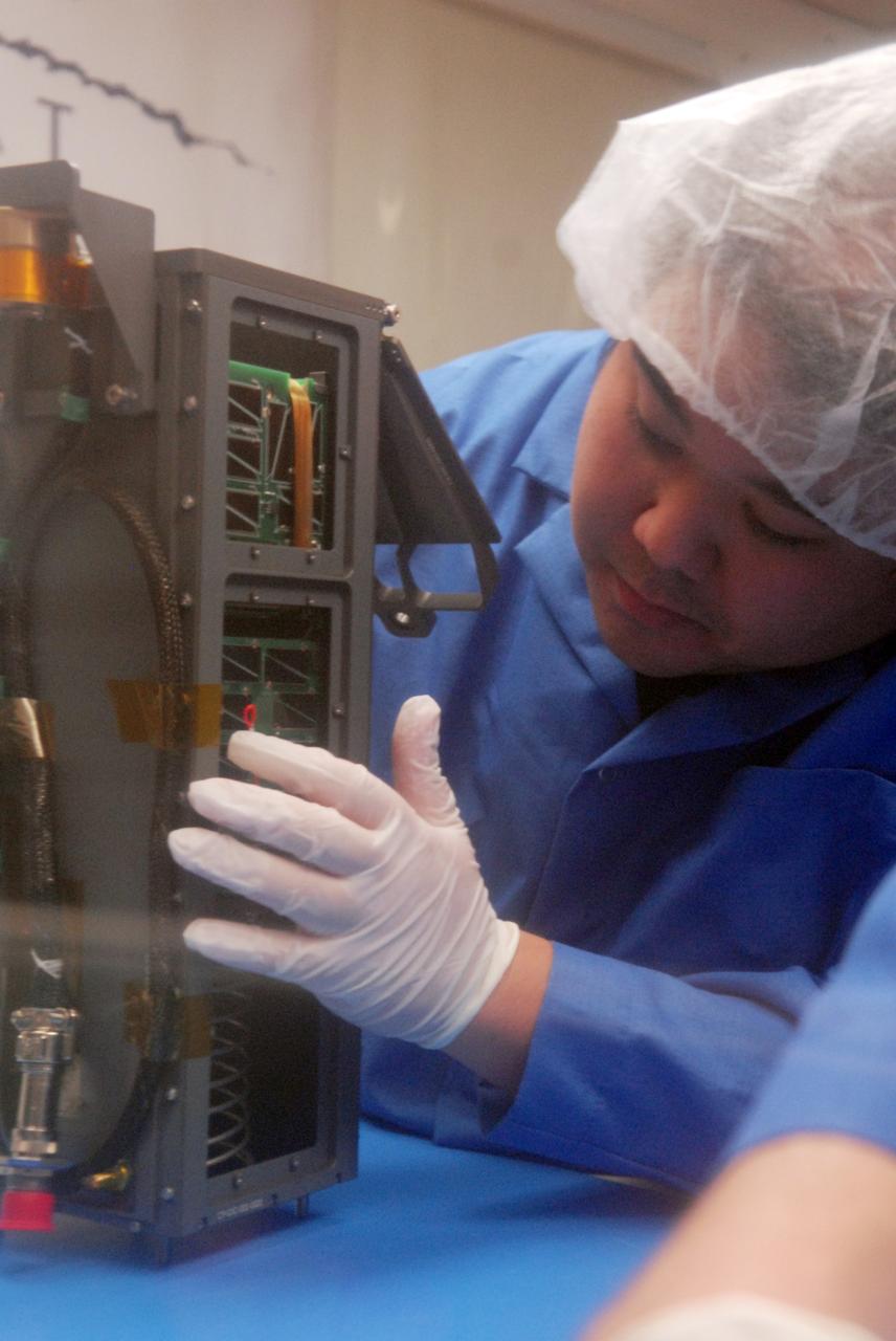 San Luis Obispo, CA - Roland Coelho, a student at California Polytechnic State University, inspects the integration alignment of mini research satellites or CubeSats into a Poly Picosatellite Orbital Deployer, or PPOD, container. The PPOD and CubeSat Project were developed by California Polytechnic State University in San Luis Obispo, Calif., and Stanford University’s Space Systems Development Lab for use on NASA’s Educational Launch of Nanosatellite, or ELaNa missions. Each CubeSat measures about four inches cubed; about the same volume as a quart. The CubeSats weigh about 2.2 pounds, must conform to standard aerospace materials and must operate without propulsion.  U.S. Air Force Photo/Mr. Jerry E. Clemens, Jr.