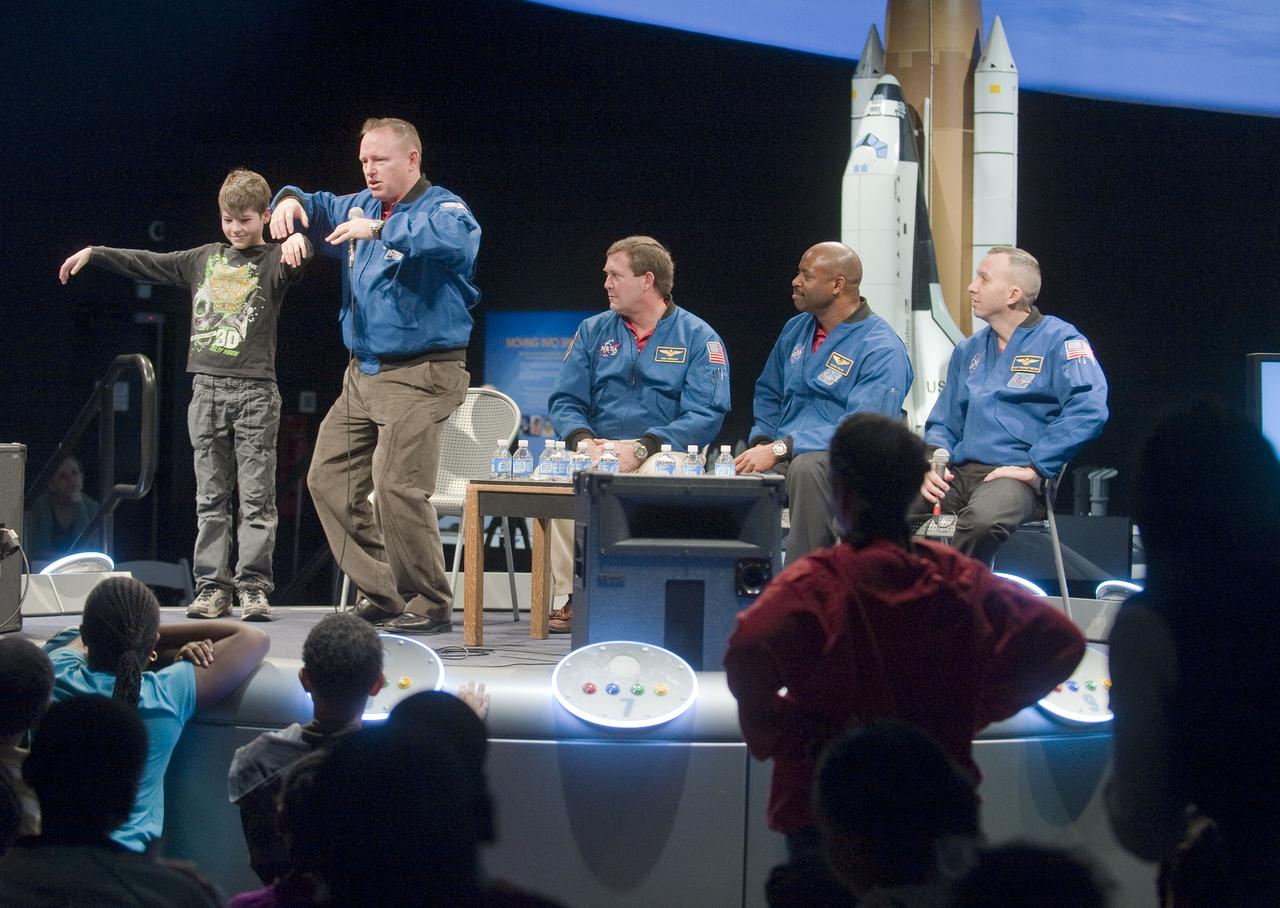 NASA STS-129 mission pilot Barry Wilmore, second from left, demonstrates weightlessness in space with Trent Petersen, a student at Stuart-Hobson Middle School, left, as crew members Mike Foreman, Leland Melvin and Randy Bresnick, right, look on during a presentation about their recent mission, Thursday, Jan. 14, 2010, at the Smithsonian National Air and Space Museum in Washington. Photo Credit: (NASA/Paul E. Alers)