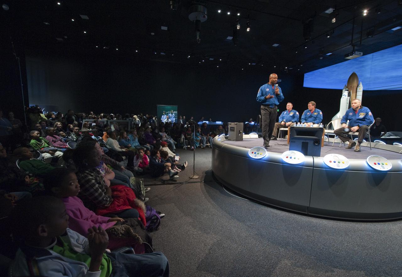NASA STS-129 mission specialist Leland Melvin, standing, speaks to students assembled as fellow crew members Barry Wilmore, seated left, Mike Foreman and Randy Bresnick, seated right, look on during a presentation about their recent mission, Thursday, Jan. 14, 2010, at the Smithsonian National Air and Space Museum in Washington. Photo Credit: (NASA/Paul E. Alers)