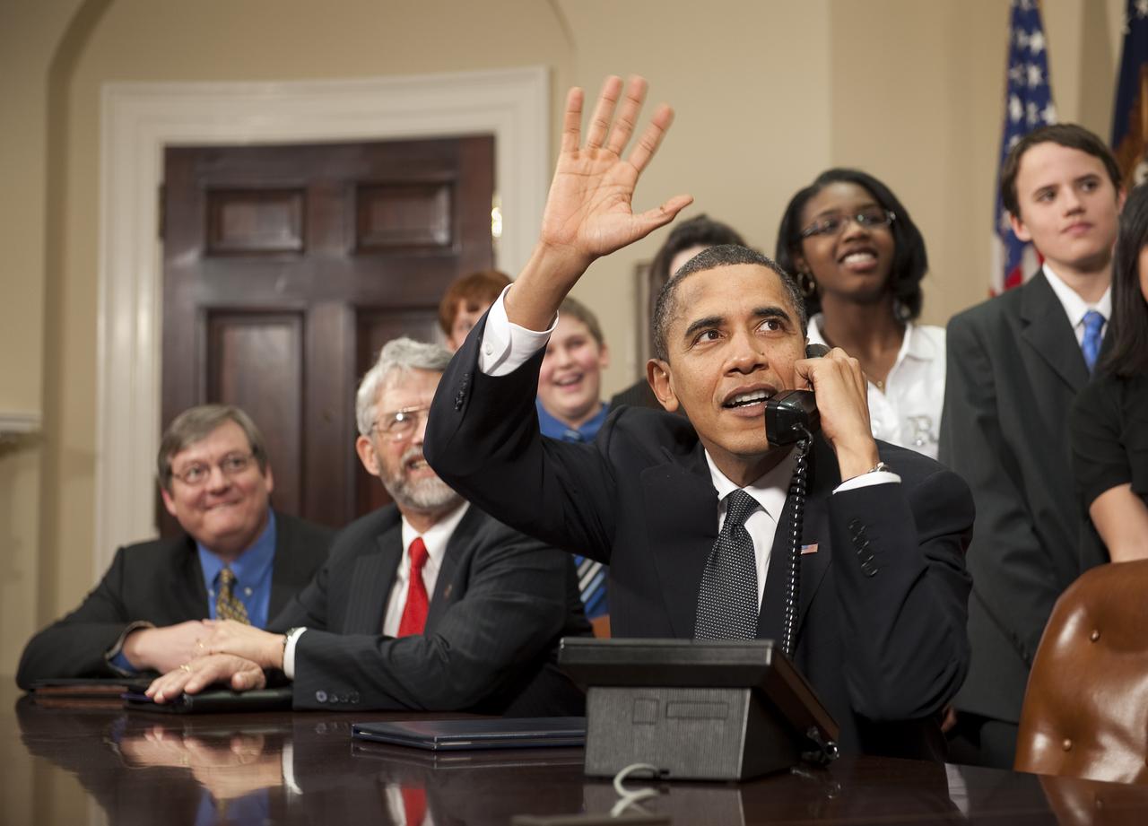 U.S. President Barack Obama, accompanied by members of Congress and middle school children,  waves as he talks on the phone from the Roosevelt Room of the White House to astronauts on the International Space Station, Wednesday, Feb. 17, 2010 in Washington. Photo Credit: (NASA/Bill Ingalls)
