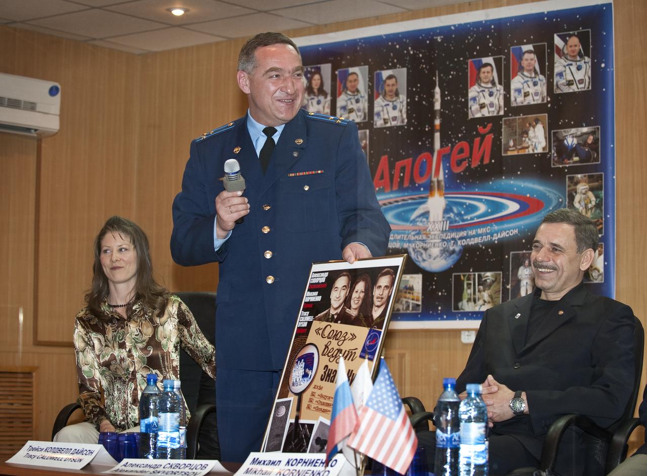 Expedition 23 Soyuz Commander Alexander Skvortsov, center, holds up a poster of the Expedition 23 crew while Flight Engineer Tracy Caldwell Dyson and Flight Engineer Mikhail Kornienko, right, smile during the State Commission meeting held at the Cosmonaut Hotel, Thursday, April 1, 2010 in Baikonur, Kazakhstan.  The State Commission meeting approves the Soyuz launch of Caldwell Dyson, Skvortsov and Kornienko to the International Space Station.  Photo Credit: (NASA/Bill Ingalls)