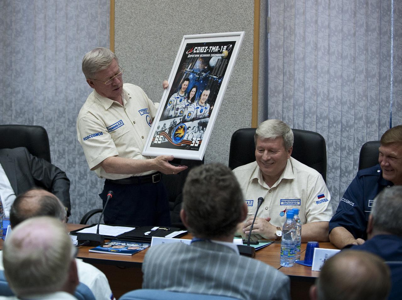 Head of the Russian Federal Space Agency, Anatoly Perminov holds a poster given to him by the crew of Expedition 24 during the State Commission meeting to approve the Soyuz launch of Expedition 24 Flight Engineers Doug Wheelock, Shannon Walker and Soyuz Commander Fyodor Yurchikhin on Monday, June 14, 2010 in Baikonur, Kazakhstan.  Photo Credit: (NASA/Carla Cioffi)