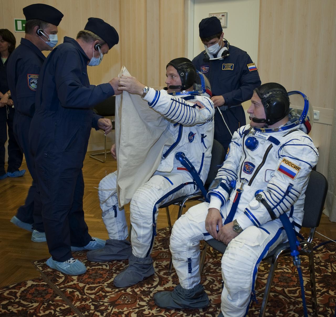 Expedition 24 NASA Flight Engineer Doug Wheelock, left, of the U.S. and Soyuz Commander Fyodor Yurchikhin have their Russian Sokol suits prepared for launch by a technician at the Baikonur Cosmodrome in Baikonur, Kazakhstan, Tuesday, June 15, 2010. Wheelock, Yurchikhin and Flight Engineer Shannon Walker launched in their Soyuz TMA-19 rocket from the Baikonur Cosmodrome in Kazakhstan on Wednesday, June 16, 2010. (Photo Credit: NASA/Carla Cioffi)