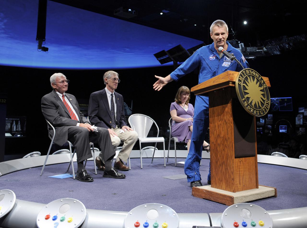 STS-132 astronaut Piers Sellers, at podium, acknowleges museum director Ret. Gen. John R. "Jack" Dailey, seated left, and NASA astrophycisist Dr. John Mather, center, during a presentation, Tuesday, July 27, 2010, at the Smithsonian National Air and Space Museum in Washington. Sellers returned a replica of the Nobel Prize that is in the museum's collection and was flown aboard STS-132 Atlantis. The prize was won by Mather and University of California, Berkeley researcher George Smoot in 2006 for their work using the Cosmic Background Explorer Satellite to understand the big-bang theory of the universe.Photo Credit: (NASA/Paul E. Alers)