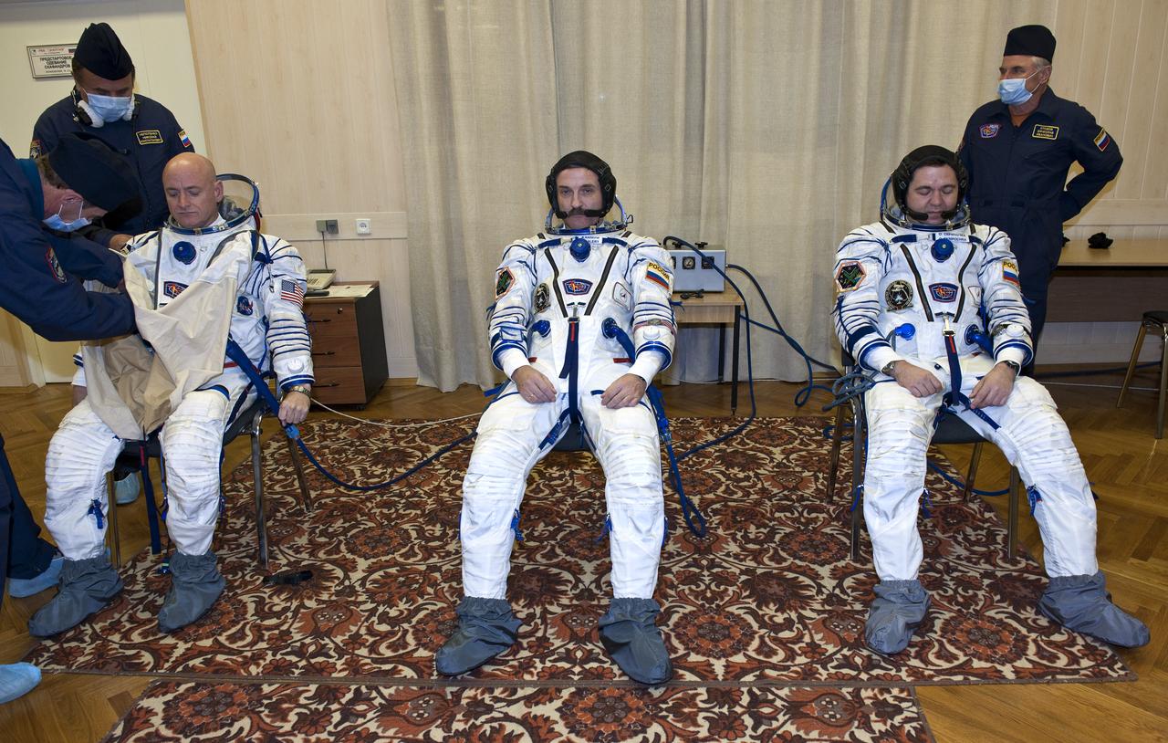 Expedition 25 NASA Flight Engineer Scott Kelly of the U.S., left, Soyuz Commander Alexander Kaleri and Flight Engineer Oleg Skripochka, right, have their Russian Sokol suits prepared for launch by technicians at the Baikonur Cosmodrome in Kazakhstan, Friday, Oct. 8, 2010. (Photo Credit: NASA/Carla Cioffi)