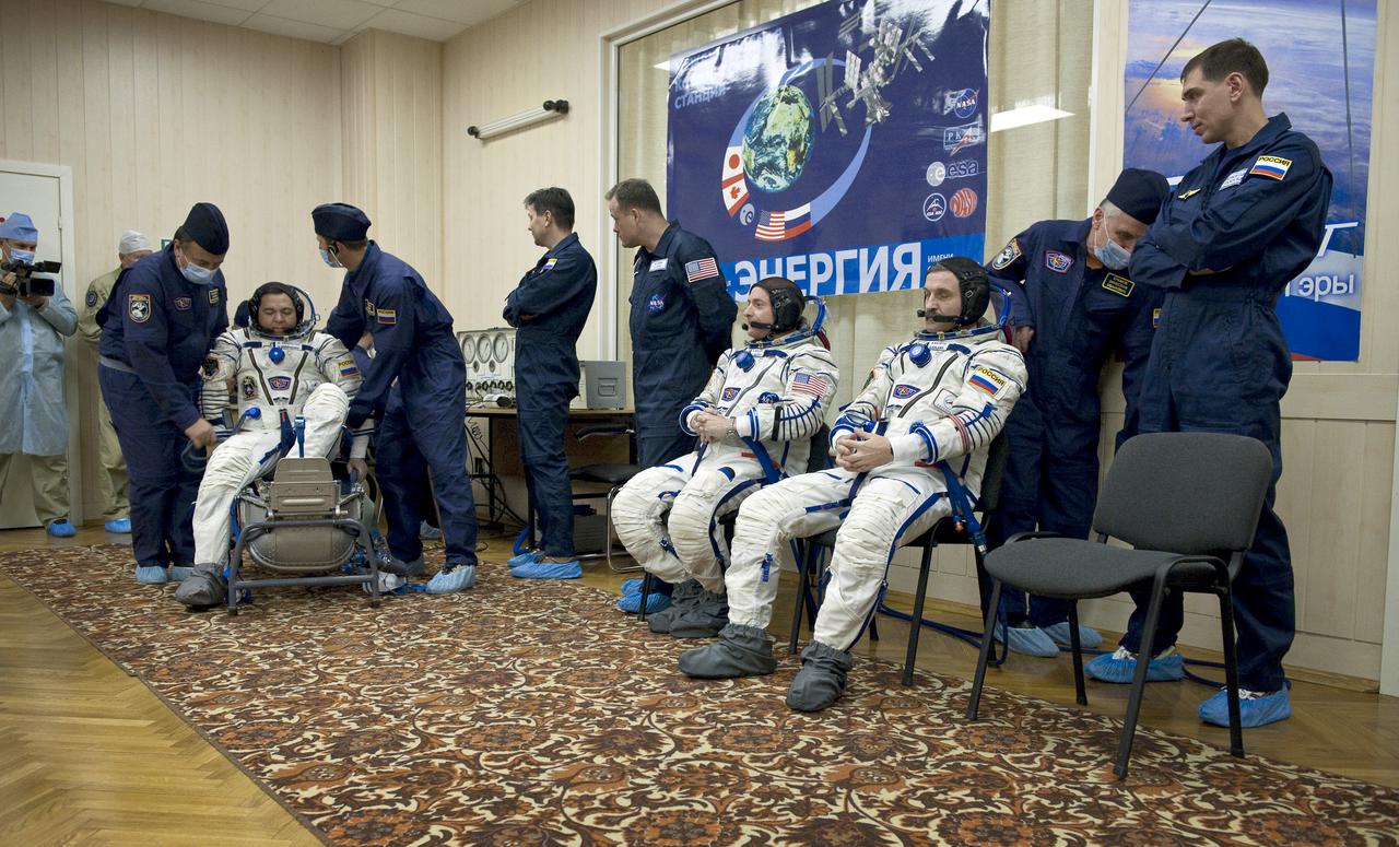 Expedition 25 Flight Engineer Oleg Skripochka, far left, has his Russian Sokol Suit pressure checked at the Baikonur Cosmodrome in Kazakhstan on Friday, Oct. 8, 2010. Fellow crew members Flight Engineer Scott Kelly, fourth from right, and Soyuz Commander Alexander Kaleri, third from right, look on. (Photo Credit: NASA/Carla Cioffi)