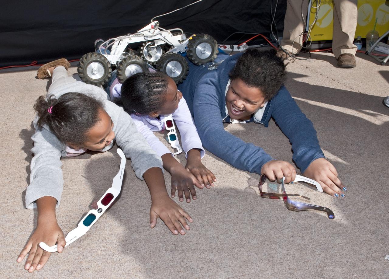 Children react as a tiny Mars Rover rolls over their backs at the USA Science and Engineering Festival, Saturday, Oct. 23, 2010, at Freedom Plaza in Washington. NASA, joined with more than 500 science organizations this weekend to inspire the next generation of scientists and engineers during the first national science and engineering festival held in the nation's capital. Photo Credit: (NASA/Paul E. Alers)