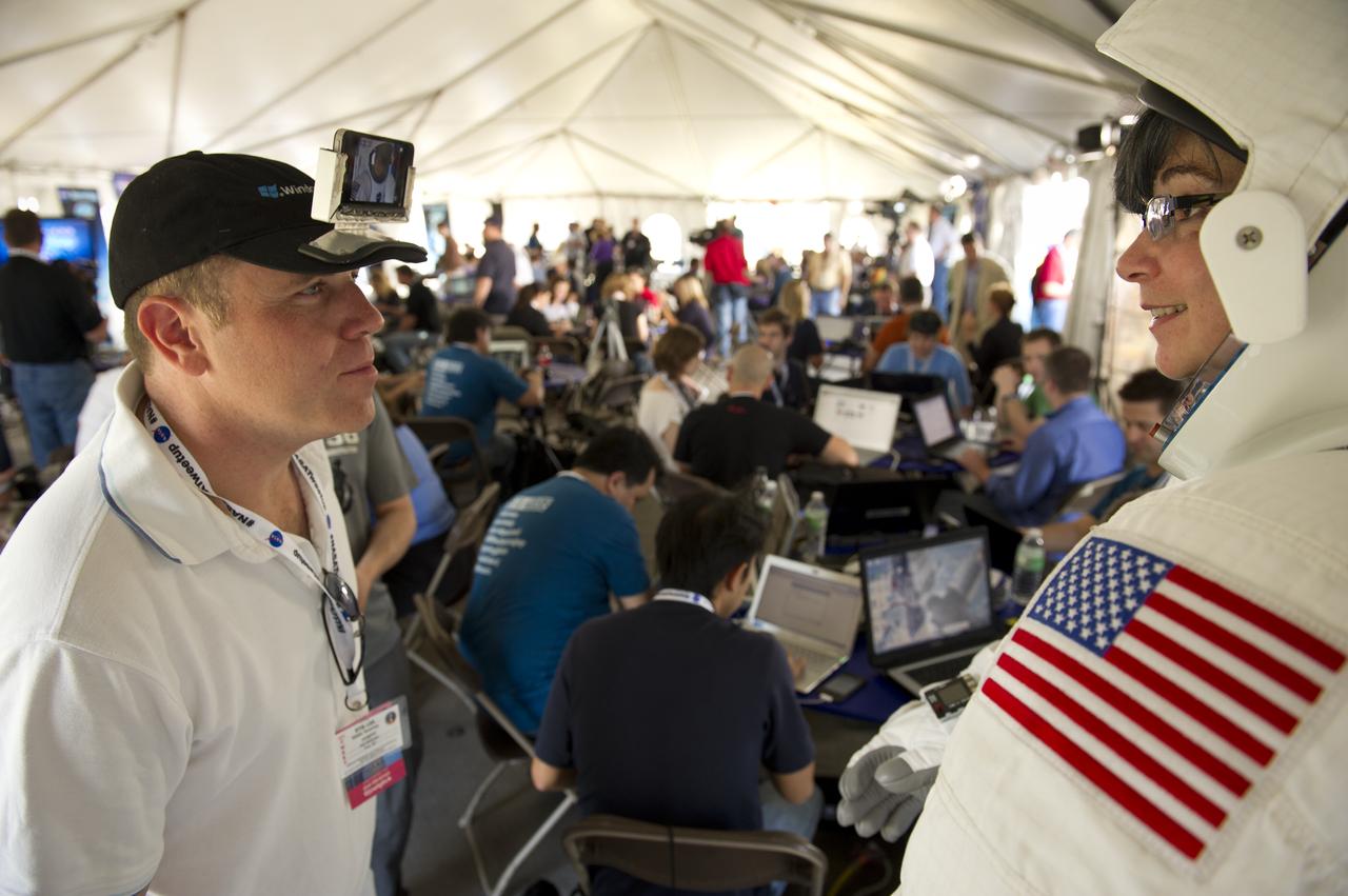 sends streaming live video via a mobile phone attached to his hat to his website of Phylise Banner, who goes by @Phylisebanner on Twitter, as she stands in an astronaut suit on display during the tweetup on Monday, Nov., 1, 2010 at the NASA Kennedy Space Center in Cape Canaveral, Fla.  Photo Credit: (NASA/Bill Ingalls)