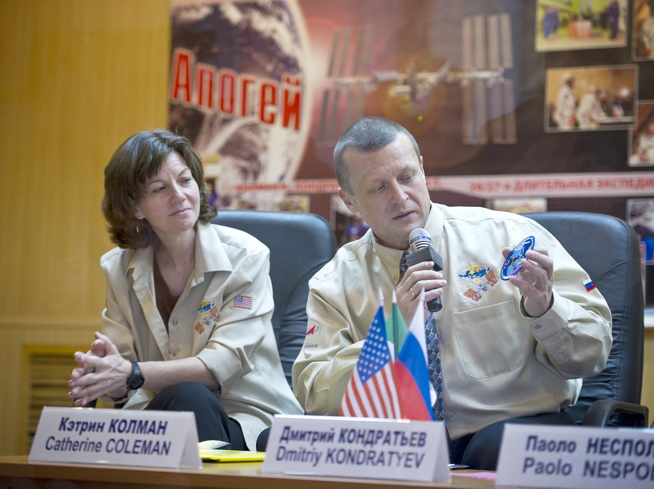 Expedition 26 Soyuz Commander Dmitry Kondratyev holds a patch as Expedition 26 Flight Engineer Catherine Coleman, left, looks on at the State Commission press conference held at the Cosmonaut Hotel in Baikonur, Kazakhstan on Tuesday, Dec. 14, 2010. Photo Credit: (NASA/Carla Cioffi)