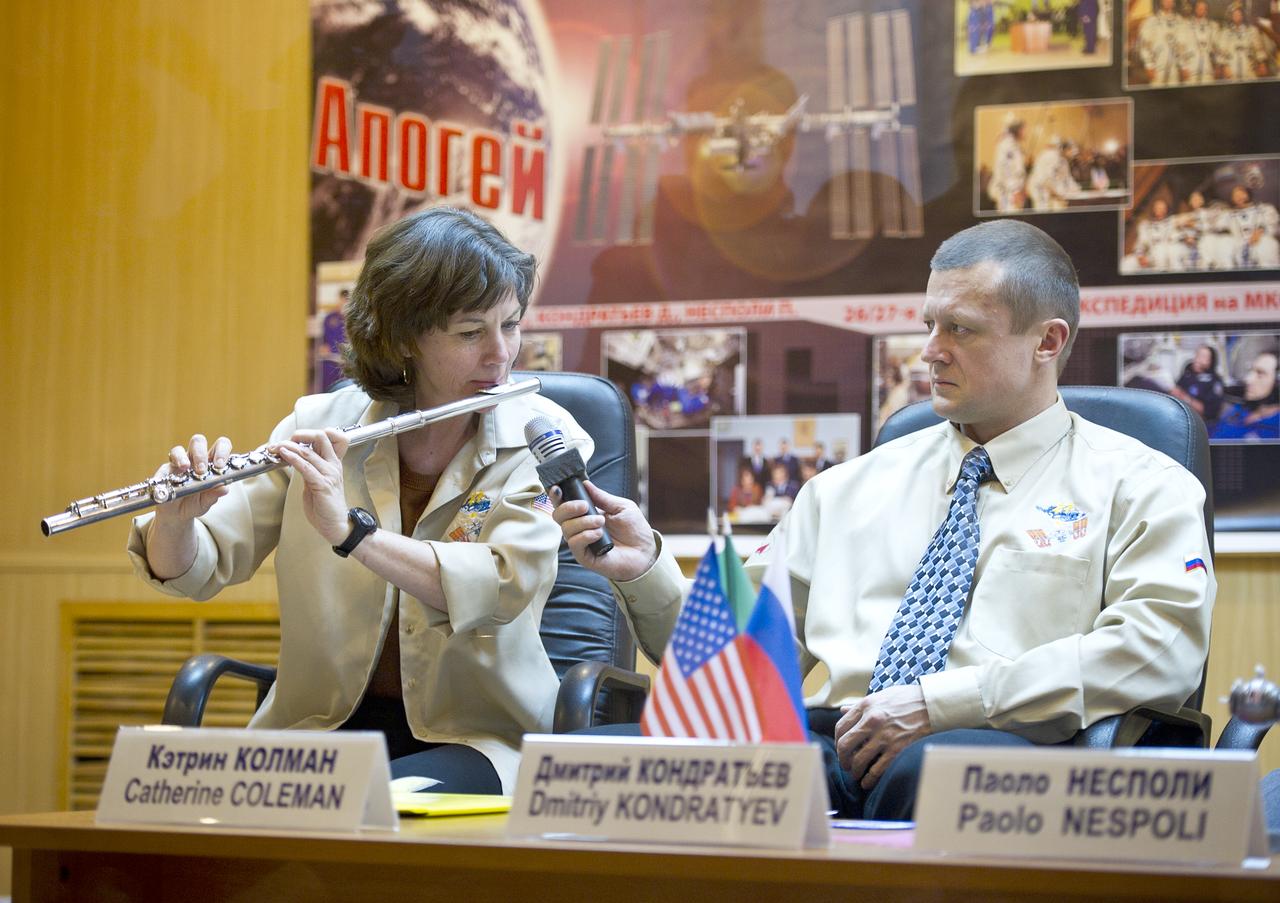 Expedition 26 Flight Engineer Catherine Coleman plays "A Hallelujah" by Leonard Cohen on the flute as Dmitry Kondratyev, Expedition 26 Soyuz Commander looks on at the State Commission press conference held at the Cosmonaut Hotel in Baikonur, Kazakhstan on Tuesday, Dec. 14, 2010. Photo Credit: (NASA/Carla Cioffi)