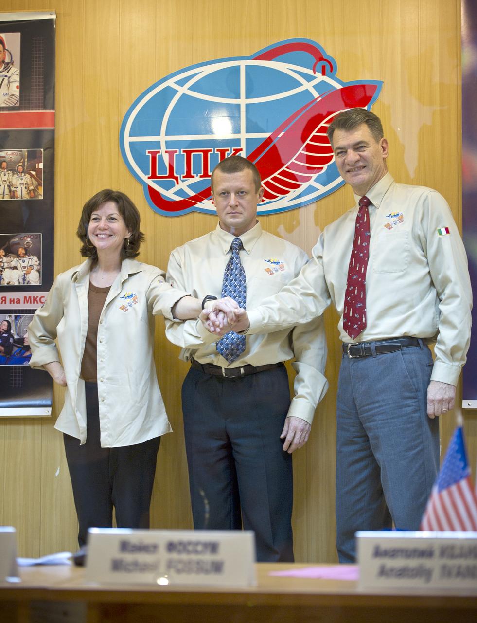Expedition 26 Flight Engineer Catherine Coleman, left, Expedition 26 Soyuz Commander Dmitry Kondratyev and Flight Engineer Paolo Nespoli, right, join hands following the State Commission press conference held at the Cosmonaut Hotel in Baikonur, Kazakhstan on Tuesday, Dec. 14, 2010. Photo Credit: (NASA/Carla Cioffi)