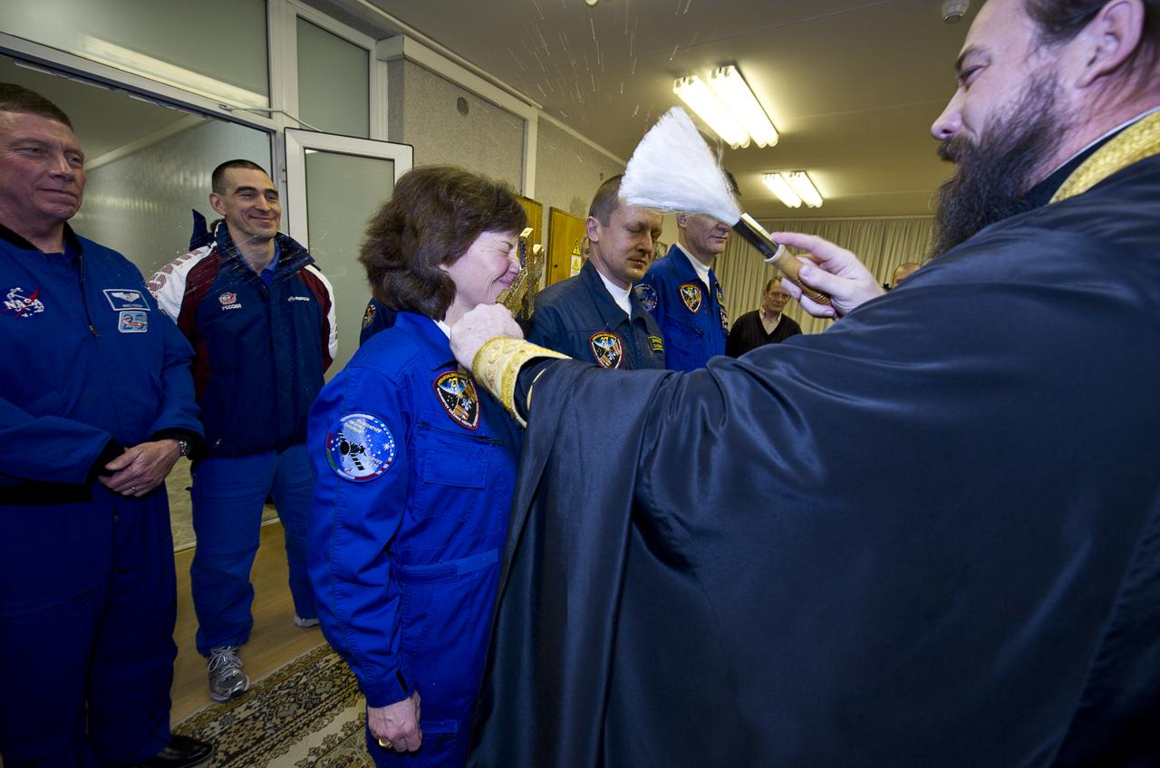 NASA Expedition 26 NASA Flight Engineer Catherine Coleman, center, is seen receiving the traditional blessing from a Russian Orthodox priest at the Cosmonaut Hotel the evening before her Soyuz launch to the International Space Station on Wednesday, Dec. 15, 2010 in Baikonur, Kazakhstan. Coleman, Soyuz Commander Dmitry Kondratyev and European Space Agency astronaut Paolo Nespoli launched to the ISS onboard a Soyuz rocket the following morning from the Baikonur Cosmodrome in Kazakhstan. Photo Credit: (NASA/Carla Cioffi)