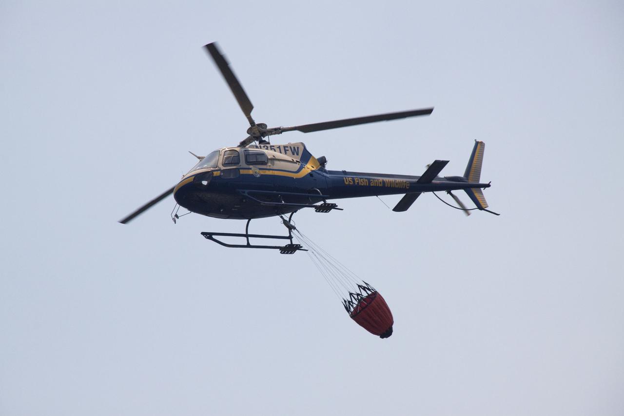 CAPE CANAVERAL, Fla. -- At NASA's Kennedy Space Center in Florida, a helicopter collects water from the Turn Basin to douse a nearby brush fire. The fire was spotted in a rural area southeast of Kennedy’s Press Site approximately three miles away from Launch Pad 39A, where space shuttle Endeavour awaits liftoff on the STS-134 mission to the International Space Station. The fire is being contained by crews from Kennedy and the U.S. Fish and Wildlife Service and smoke is not expected to impact launch. Photo credit: NASA_Jack Pfaller