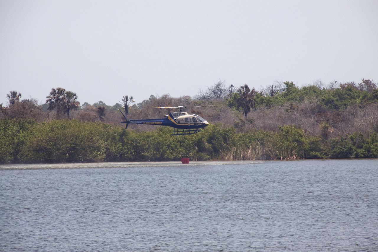 CAPE CANAVERAL, Fla. -- At NASA's Kennedy Space Center in Florida, a helicopter collects water from the Turn Basin to douse a nearby brush fire. The fire was spotted in a rural area southeast of Kennedy’s Press Site approximately three miles away from Launch Pad 39A, where space shuttle Endeavour awaits liftoff on the STS-134 mission to the International Space Station. The fire is being contained by crews from Kennedy and the U.S. Fish and Wildlife Service and smoke is not expected to impact launch. Photo credit: NASA_Jack Pfaller