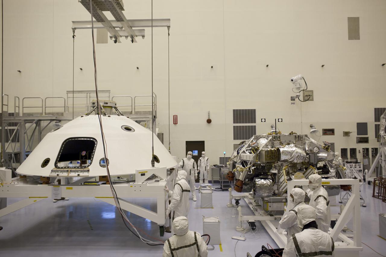 CAPE CANAVERAL, Fla. – In the Payload Hazardous Servicing Facility at NASA's Kennedy Space Center in Florida, technicians, using an overhead crane, lift the backshell for NASA's Mars Science Laboratory (MSL) rover, Curiosity. The backshell, a protective cover which carries the parachute and several components used during later stages of entry, descent and landing, will be encapsulated over the rover (seen to the right). A United Launch Alliance Atlas V-541 configuration will be used to loft MSL into space. MSL's components include a compact car-sized rover, Curiosity, which has 10 science instruments designed to search for evidence on whether Mars has had environments favorable to microbial life, including chemical ingredients for life. The unique rover will use a laser to look inside rocks and release its gasses so that the rover’s spectrometer can analyze and send the data back to Earth. MSL is scheduled to launch Nov. 25 with a window extending to Dec. 18 and arrival at Mars Aug. 2012. For more information, visit http:__www.nasa.gov_msl. Photo credit: NASA_Dimitri Gerondidakis