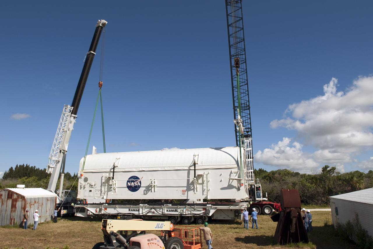 CAPE CANAVERAL, Fla. -- Cranes are attached to payload canister #1 to lift it from the transporter that delivered it to the Reutilization, Recycling and Marketing Facility on Ransom Road at NASA's Kennedy Space Center in Florida.  The two payload canisters used to transport space shuttle payloads to the launch pad for installation in the shuttles' cargo bays are being decommissioned following the end of the Space Shuttle Program. Each canister weighs 110,000 pounds and is 65 feet long, 22 feet wide, and 18 feet, 7 inches high.  The canisters were prescreened through NASA Headquarters as possible artifacts, but their size makes them difficult to transport to locations off the center. Federal and state agencies now will be given the opportunity to screen the canisters for potential use before a final decision is made on their disposition.  For more information, visit http:__www.nasa.gov_centers_kennedy_pdf_167403main_CRF-06.pdf. Photo credit: NASA_Jim Grossmann