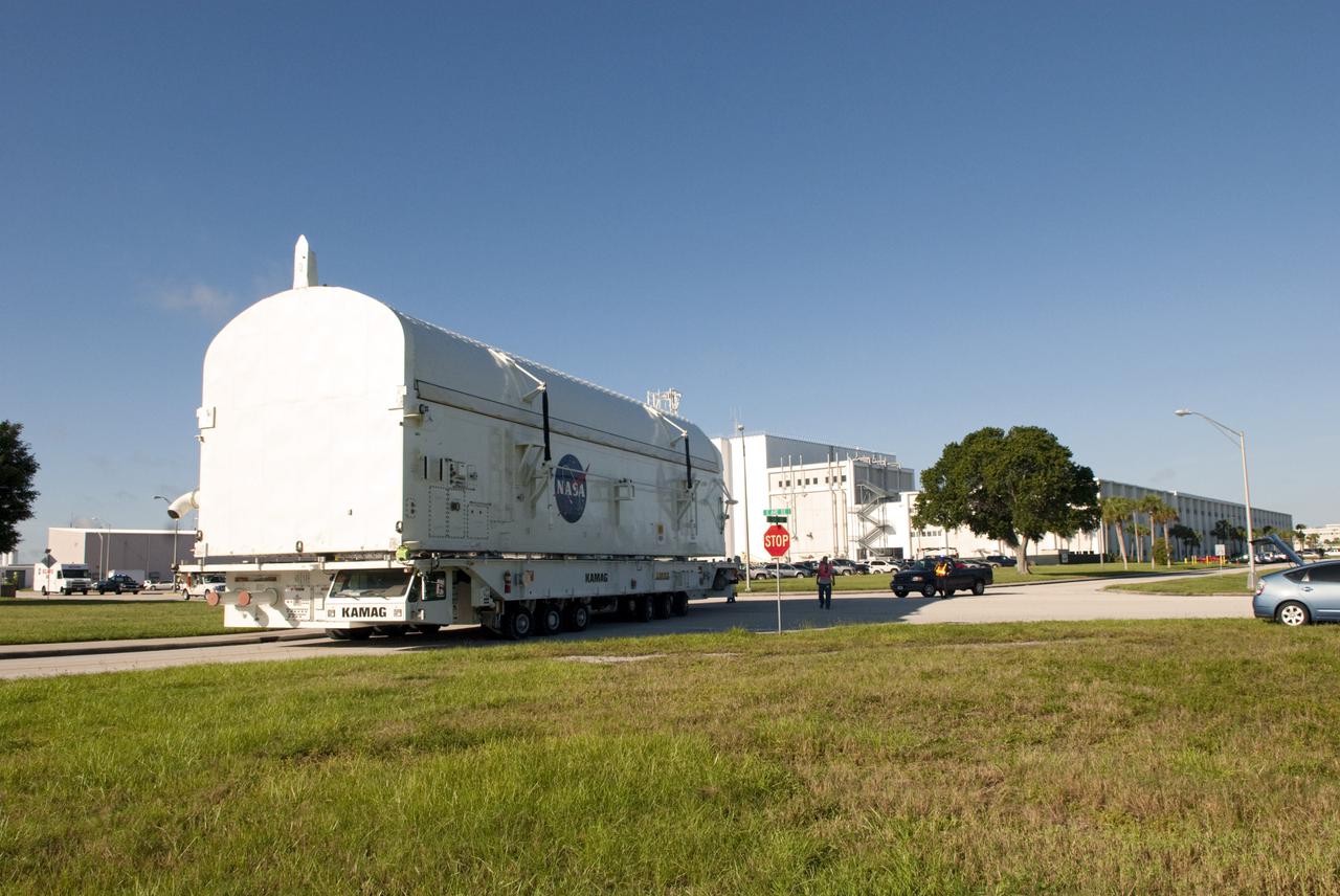 CAPE CANAVERAL, Fla. -- Payload canister #2 passes near the Operations and Checkout Building, in the background, on its way from the Canister Rotation Facility at NASA's Kennedy Space Center in Florida to the Reutilization, Recycling and Marketing Facility on Ransom Road.  The canister will stop in front of the Space Station Processing Facility for a group employee photo opportunity before continuing to Ransom Road.  The two payload canisters used to transport space shuttle payloads to the launch pad for installation in the shuttles' cargo bays are being decommissioned following the end of the Space Shuttle Program. Each canister weighs 110,000 pounds and is 65 feet long, 22 feet wide, and 18 feet, 7 inches high.  The canisters were prescreened through NASA Headquarters as possible artifacts, but their size makes them difficult to transport to locations off the center. Federal and state agencies now will be given the opportunity to screen the canisters for potential use before a final decision is made on their disposition.  For more information, visit http:__www.nasa.gov_centers_kennedy_pdf_167403main_CRF-06.pdf. Photo credit: NASA_Jim Grossmann