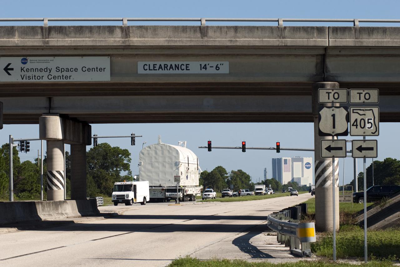 CAPE CANAVERAL, Fla. -- At NASA's Kennedy Space Center in Florida, a convoy of support vehicles travels with payload canister #2 on its move from the Canister Rotation Facility (CFR) to the Reutilization, Recycling and Marketing Facility on Ransom Road.  In the background is the 525-foot-tall Vehicle Assembly Building where the canister was rotated into a vertical position before the CRF took over the task in 1993.  The two payload canisters used to transport space shuttle payloads to the launch pad for installation in the shuttles' cargo bays are being decommissioned following the end of the Space Shuttle Program. Each canister weighs 110,000 pounds and is 65 feet long, 22 feet wide, and 18 feet, 7 inches high.  The canisters were prescreened through NASA Headquarters as possible artifacts, but their size makes them difficult to transport to locations off the center. Federal and state agencies now will be given the opportunity to screen the canisters for potential use before a final decision is made on their disposition.  For more information, visit http:__www.nasa.gov_centers_kennedy_pdf_167403main_CRF-06.pdf. Photo credit: NASA_Jim Grossmann