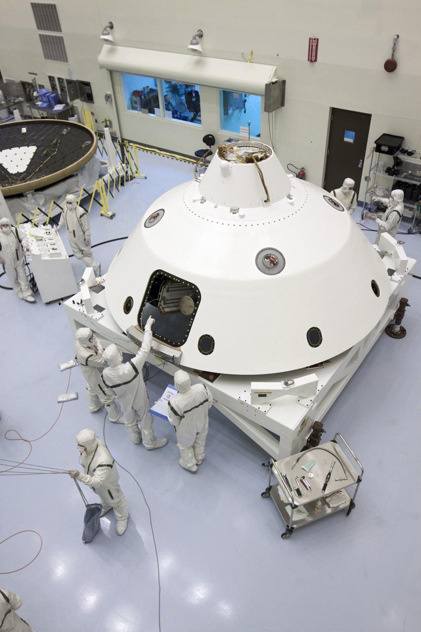 CAPE CANAVERAL, Fla. – In the Payload Hazardous Servicing Facility at NASA’s Kennedy Space Center in Florida, technicians stand next to NASA's Mars Science Laboratory (MSL) mission aeroshell as, in the foreground, a technician guides the cruise stage onto a rotation stand. The cruise stage provides solar power, thrusters for navigation, and heat exchangers to the rover during its flight from Earth to Mars. To the back left is the MSL heat shield.  MSL's components include a car-sized rover, Curiosity, which has 10 science instruments designed to search for evidence on whether Mars has had environments favorable to microbial life, including chemical ingredients for life.  The unique rover will use a laser to look inside rocks and release its gasses so that the rover’s spectrometer can analyze and send the data back to Earth. Launch of MSL aboard a United Launch Alliance Atlas V rocket is scheduled for Nov. 25 from Space Launch Complex 41 on Cape Canaveral Air Force Station in Florida. For more information, visit http:__www.nasa.gov_msl. Photo credit: NASA_Glenn Benson