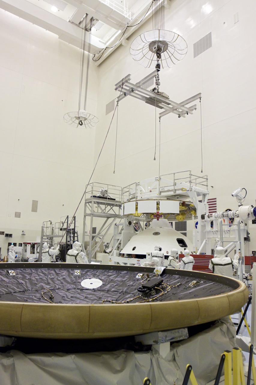 CAPE CANAVERAL, Fla. – In the Payload Hazardous Servicing Facility at NASA’s Kennedy Space Center in Florida, technicians prepare to attach an overhead crane to NASA's Mars Science Laboratory (MSL) mission aeroshell, (containing the compact car-sized rover Curiosity), which will be mated to the cruise stage. The cruise stage provides solar power, thrusters for navigation, and heat exchangers to the rover during its flight from Earth to Mars. In the foreground is the MSL heat shield. The rover Curiosity has 10 science instruments designed to search for evidence on whether Mars has had environments favorable to microbial life, including chemical ingredients for life. The unique rover will use a laser to look inside rocks and release its gasses so that the rover’s spectrometer can analyze and send the data back to Earth. Launch of MSL aboard a United Launch Alliance Atlas V rocket is scheduled for Nov. 25 from Space Launch Complex 41 on Cape Canaveral Air Force Station in Florida. For more information, visit http:__www.nasa.gov_msl. Photo credit: NASA_Glenn Benson