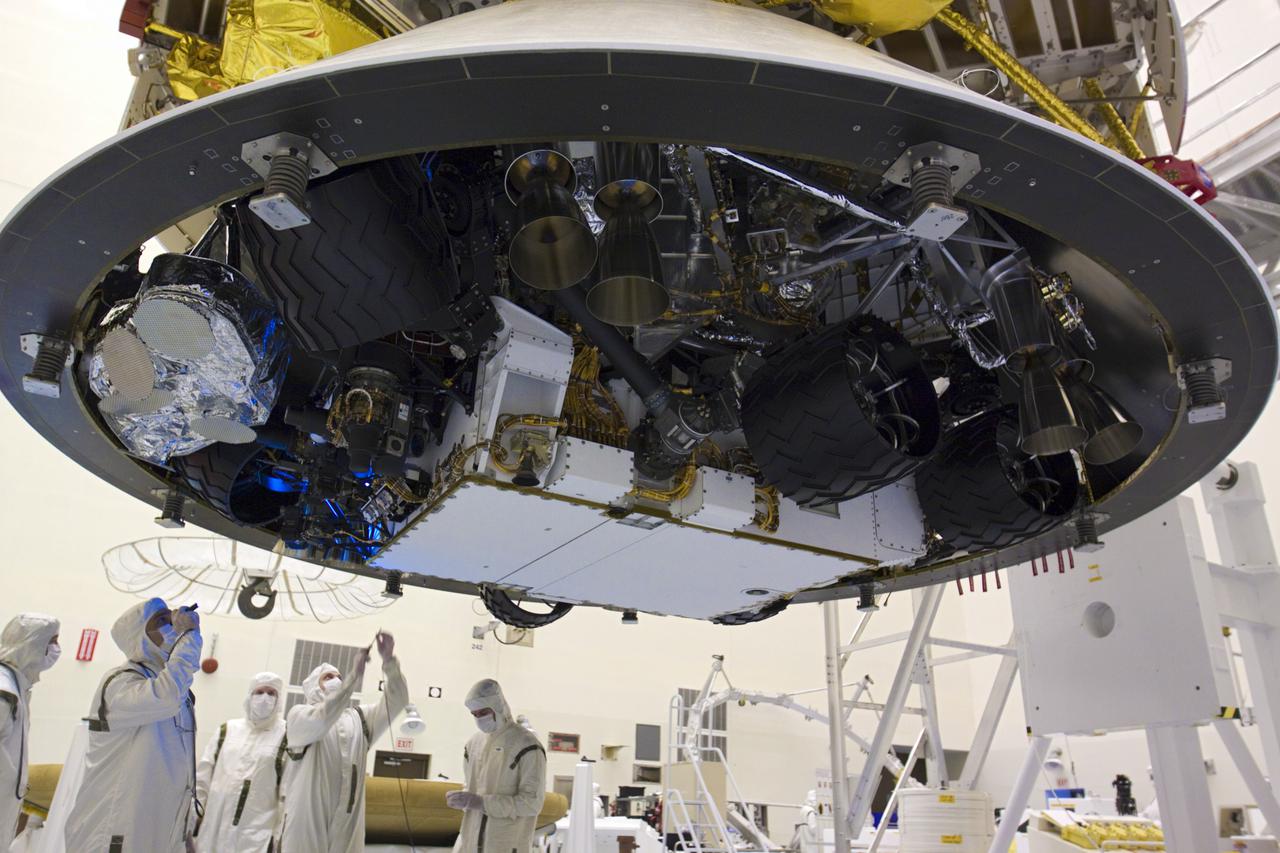 CAPE CANAVERAL, Fla. – In the Payload Hazardous Servicing Facility at NASA’s Kennedy Space Center in Florida, technicians inspect beneath NASA's Mars Science Laboratory (MSL) mission aeroshell, (containing the compact car-sized rover Curiosity), which has been mated to the cruise stage. The cruise stage provides solar power, thrusters for navigation, and heat exchangers to the rover during its flight from Earth to Mars. The rover Curiosity has 10 science instruments designed to search for evidence on whether Mars has had environments favorable to microbial life, including chemical ingredients for life. The unique rover will use a laser to look inside rocks and release its gasses so that the rover’s spectrometer can analyze and send the data back to Earth. Launch of MSL aboard a United Launch Alliance Atlas V rocket is scheduled for Nov. 25 from Space Launch Complex 41 on Cape Canaveral Air Force Station in Florida. For more information, visit http:__www.nasa.gov_msl. Photo credit: NASA_Glenn Benson