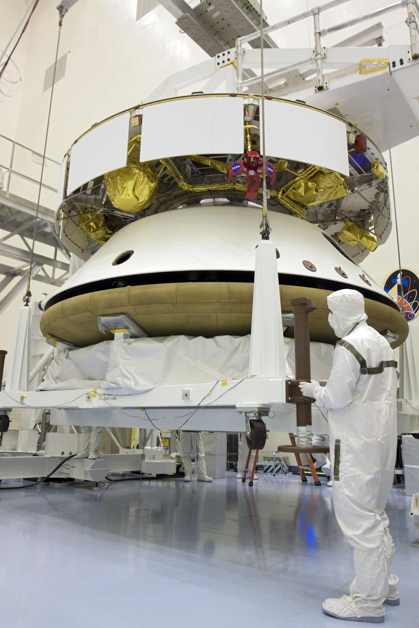 CAPE CANAVERAL, Fla. – In the Payload Hazardous Servicing Facility at NASA’s Kennedy Space Center in Florida, a technician watches as an overhead crane lifts the heat shield for integration with NASA's Mars Science Laboratory (MSL) mission aeroshell, (containing the compact car-sized rover Curiosity). Earlier, the aeroshell was mated to the cruise stage, which provides solar power, thrusters for navigation, and heat exchangers to the rover during its flight from Earth to Mars. The rover Curiosity has 10 science instruments designed to search for evidence on whether Mars has had environments favorable to microbial life, including chemical ingredients for life. The unique rover will use a laser to look inside rocks and release its gasses so that the rover’s spectrometer can analyze and send the data back to Earth. Launch of MSL aboard a United Launch Alliance Atlas V rocket is scheduled for Nov. 25 from Space Launch Complex 41 on Cape Canaveral Air Force Station in Florida. For more information, visit http:__www.nasa.gov_msl. Photo credit: NASA_Glenn Benson
