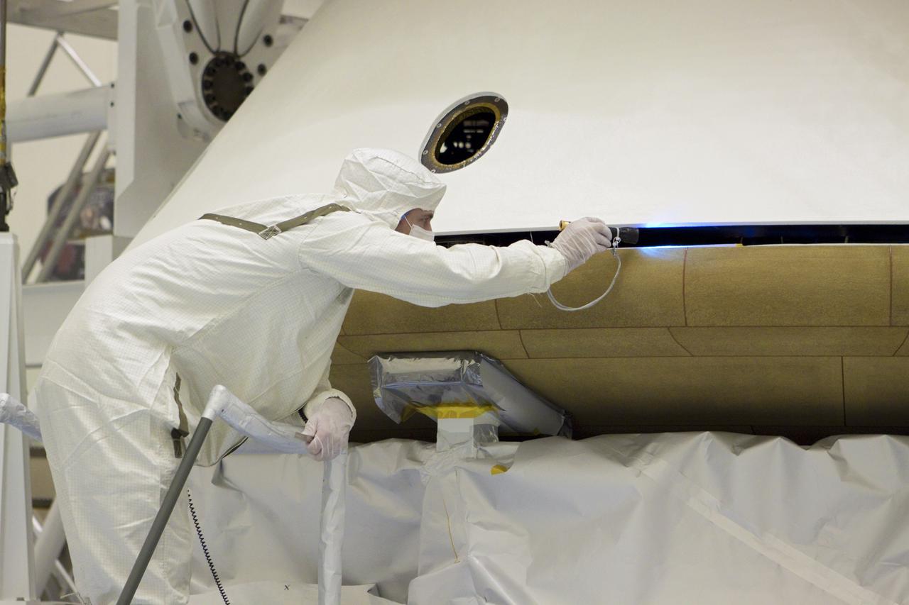CAPE CANAVERAL, Fla. – In the Payload Hazardous Servicing Facility at NASA’s Kennedy Space Center in Florida, a technician inspects the alignment of the heat shield as an overhead crane lifts it for integration with NASA's Mars Science Laboratory (MSL) mission aeroshell, (containing the compact car-sized rover Curiosity). Earlier, the aeroshell was mated to the cruise stage, which provides solar power, thrusters for navigation, and heat exchangers to the rover during its flight from Earth to Mars. The rover Curiosity has 10 science instruments designed to search for evidence on whether Mars has had environments favorable to microbial life, including chemical ingredients for life. The unique rover will use a laser to look inside rocks and release its gasses so that the rover’s spectrometer can analyze and send the data back to Earth. Launch of MSL aboard a United Launch Alliance Atlas V rocket is scheduled for Nov. 25 from Space Launch Complex 41 on Cape Canaveral Air Force Station in Florida. For more information, visit http:__www.nasa.gov_msl. Photo credit: NASA_Glenn Benson