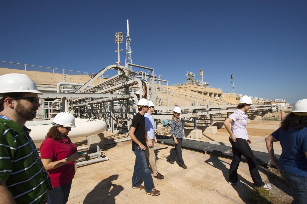 CAPE CANAVERAL, Fla. – Mechanical engineering students from Louisiana State University Christine Woodfield, right, in white shirt, Kevin Schenker, in light blue shirt, and Jacob Koch, in black shirt,  joined engineers and scientists at Launch Pad 39B at NASA's Kennedy Space Center in Florida as the students toured the facility to have a look at the flame trench. They went inside the pad structure as part of their insight. The students signed up to help designers looking for new, flame and vibration-resistant materials to line the trench. The students are to build a scaled-down version of the flame trench that Kennedy's scientists can use to try out sample materials for the trench. If the samples work in the lab, they can be tried out in the real flame trenches at Launch Pad 39A and 39B.  The launch pad has been refurbished extensively and work is continuing to modify the pad to support a variety of launch vehicles in the future. Photo credit: NASA_Jim Grossmann